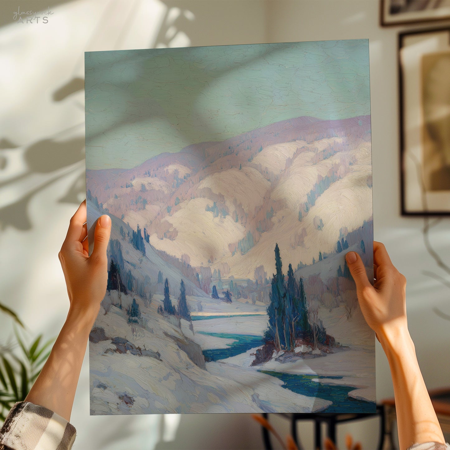 Person holding a painting of a snowy landscape with mountains and trees.