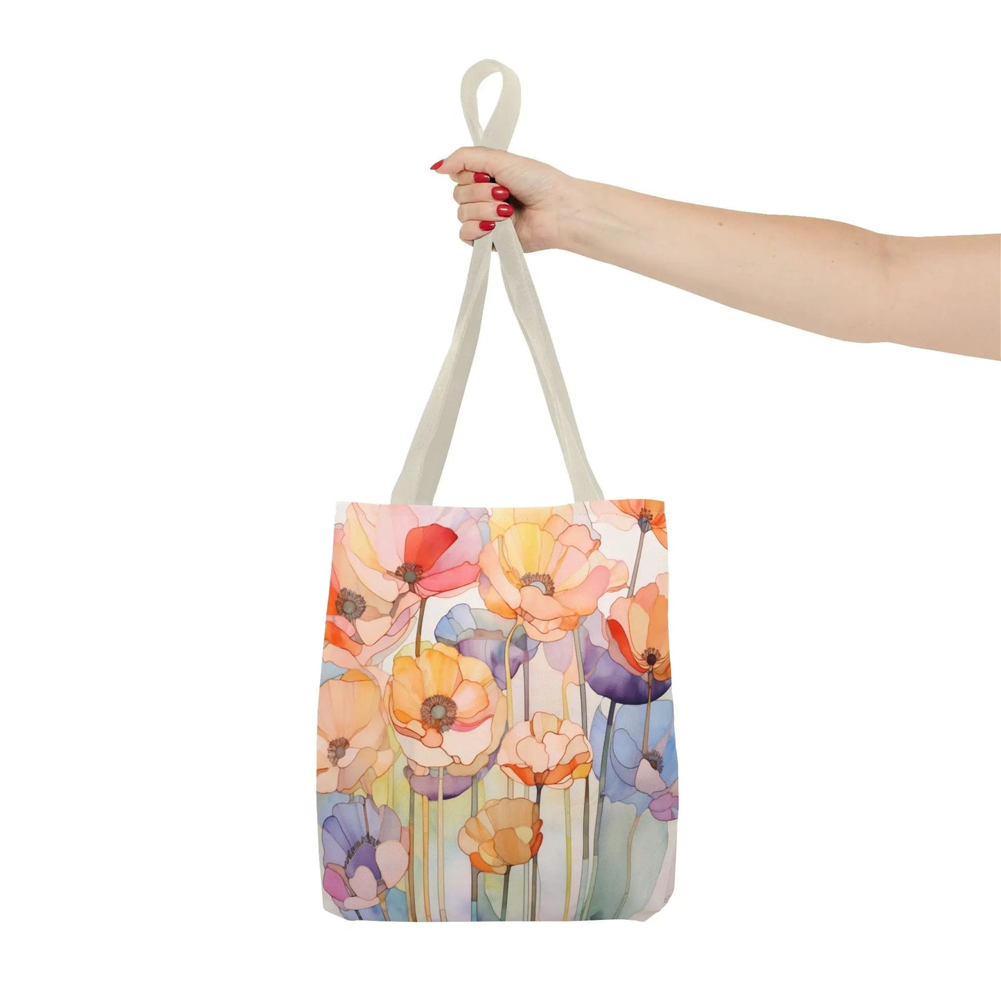 A wrist with red nail polish holds a durable polyester tote bag showcasing stained glass poppy flowers in orange, pink, purple, and yellow on a light background. Available in three sizes, the Stained Glass Poppy Flowers Tote Bag is beautifully designed.