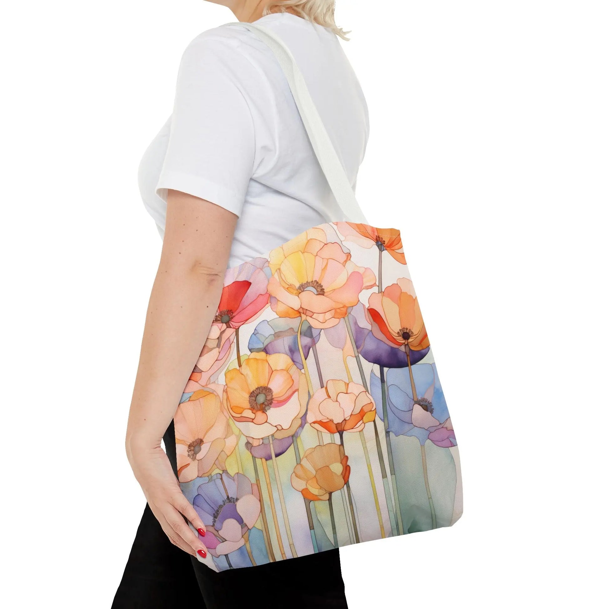 A person holds a Stained Glass Poppy Flowers Tote Bag, showcasing bold flowers in orange, pink, blue, and purple. Theyre dressed in a white shirt and black pants.