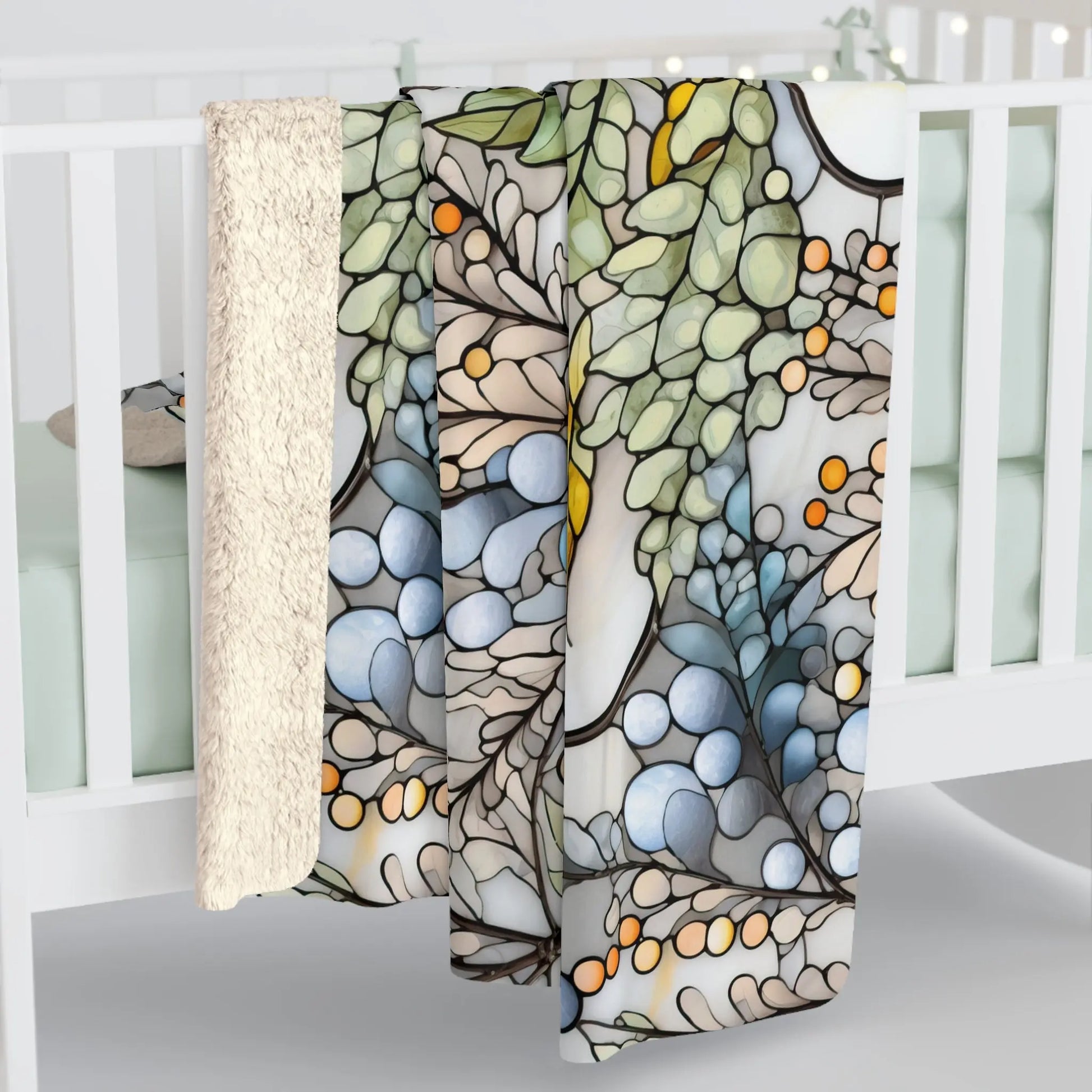 The Stained Glass Nouveau Ferns Sherpa Fleece Blanket, draped over a light green crib, features a colorful, intricate design with abstract shapes like a botanical stained glass pattern in blue, green, orange, and beige tones. Its reverse side is plush cream-colored velveteen.