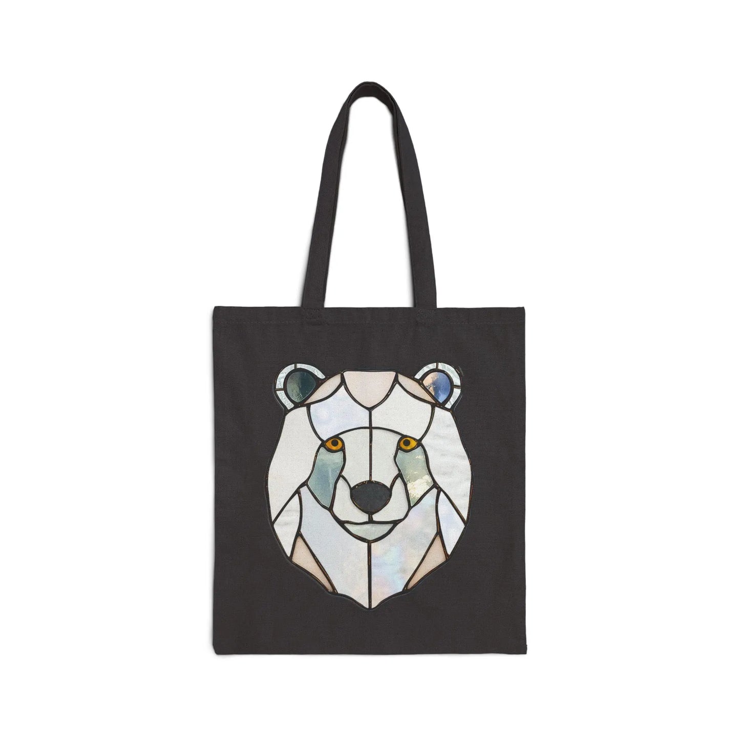 The Stained Glass Polar Bear Cotton Canvas Tote Bag by Noelle Barnes features a geometric polar bear design in shades of white, blue, and gray, with striking orange eyes that contrast beautifully against the pattern.