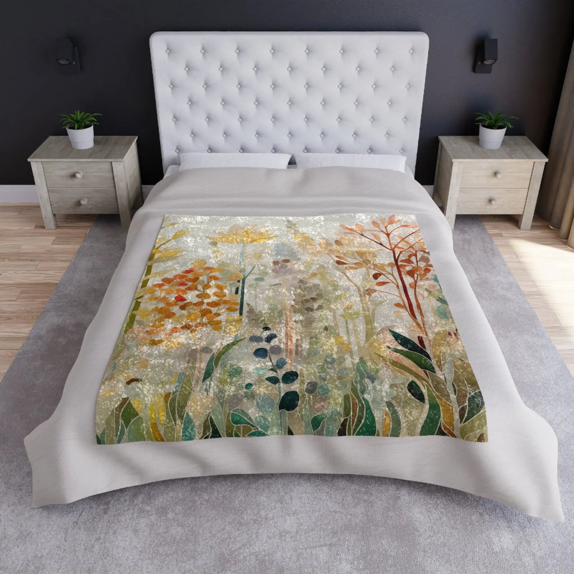 A bed with a tufted white headboard and a colorful floral duvet is enhanced by the Stained Glass Fall Flowers Crushed Velvet & Fleece Blanket. Two side tables with potted plants sit beside dark walls, wood flooring, and a gray rug. Natural light filters through the window on the right.