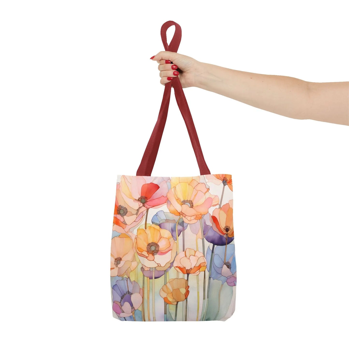 A hand with red-painted nails holds a Stained Glass Poppy Flowers Tote Bag featuring an artistic floral design with red handles on a white background.
