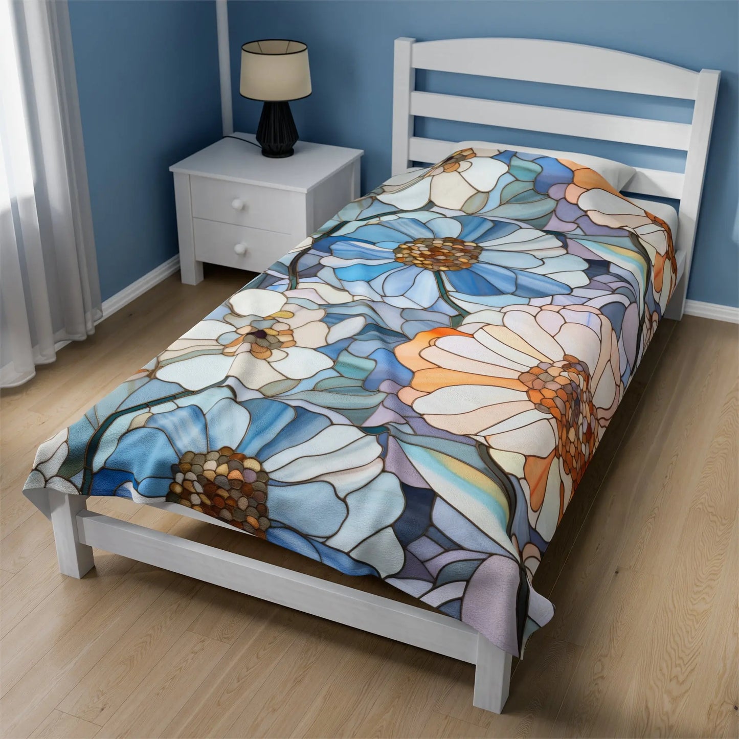 A single bed with a white frame is covered with the Stained Glass Flowers Plush Blanket, showcasing artistic flowers in blue, orange, and white. It sits by a white nightstand with a lamp in a room accented by blue walls and light wood flooring.