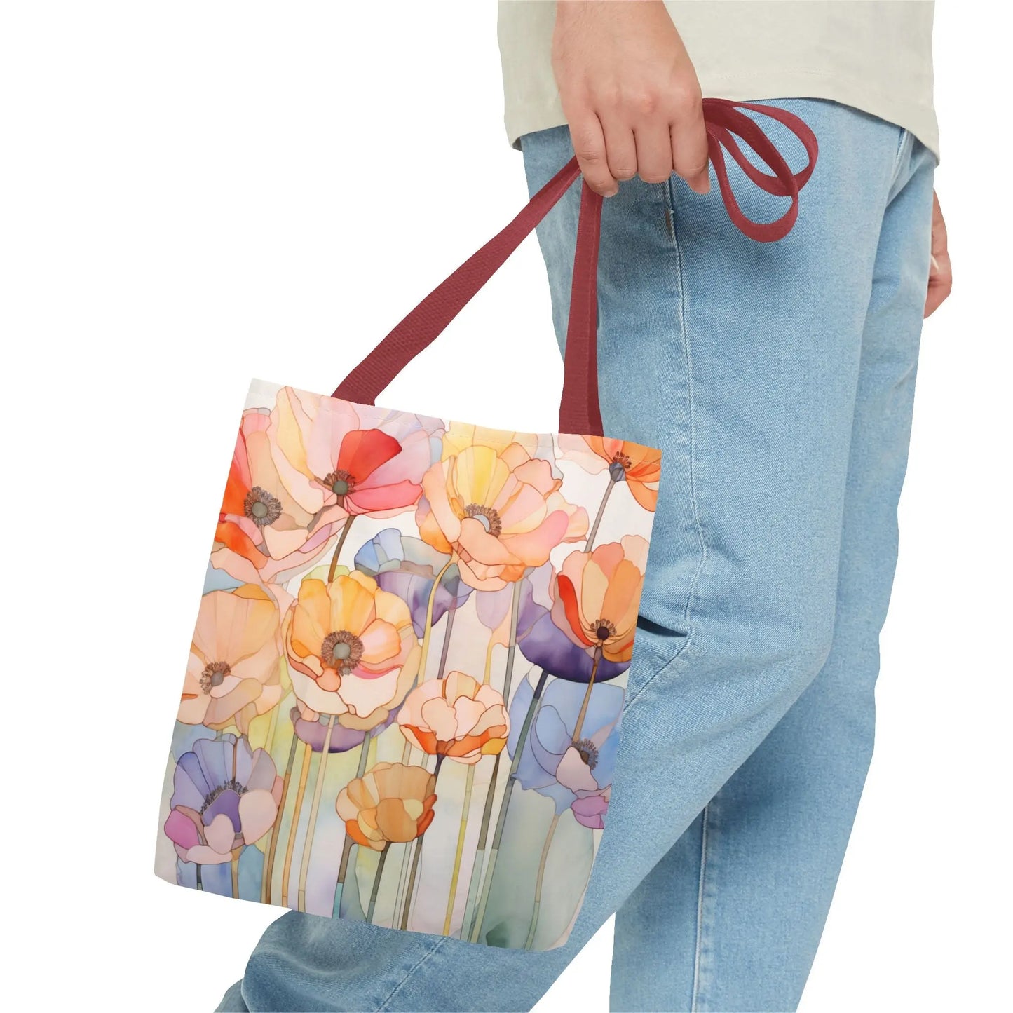 A person walks, shown from the waist down, with light blue jeans and a light shirt, carrying a Stained Glass Poppy Flowers Tote Bag in vibrant orange, yellow, pink, and purple hues. The bag is made of durable polyester with maroon handles.