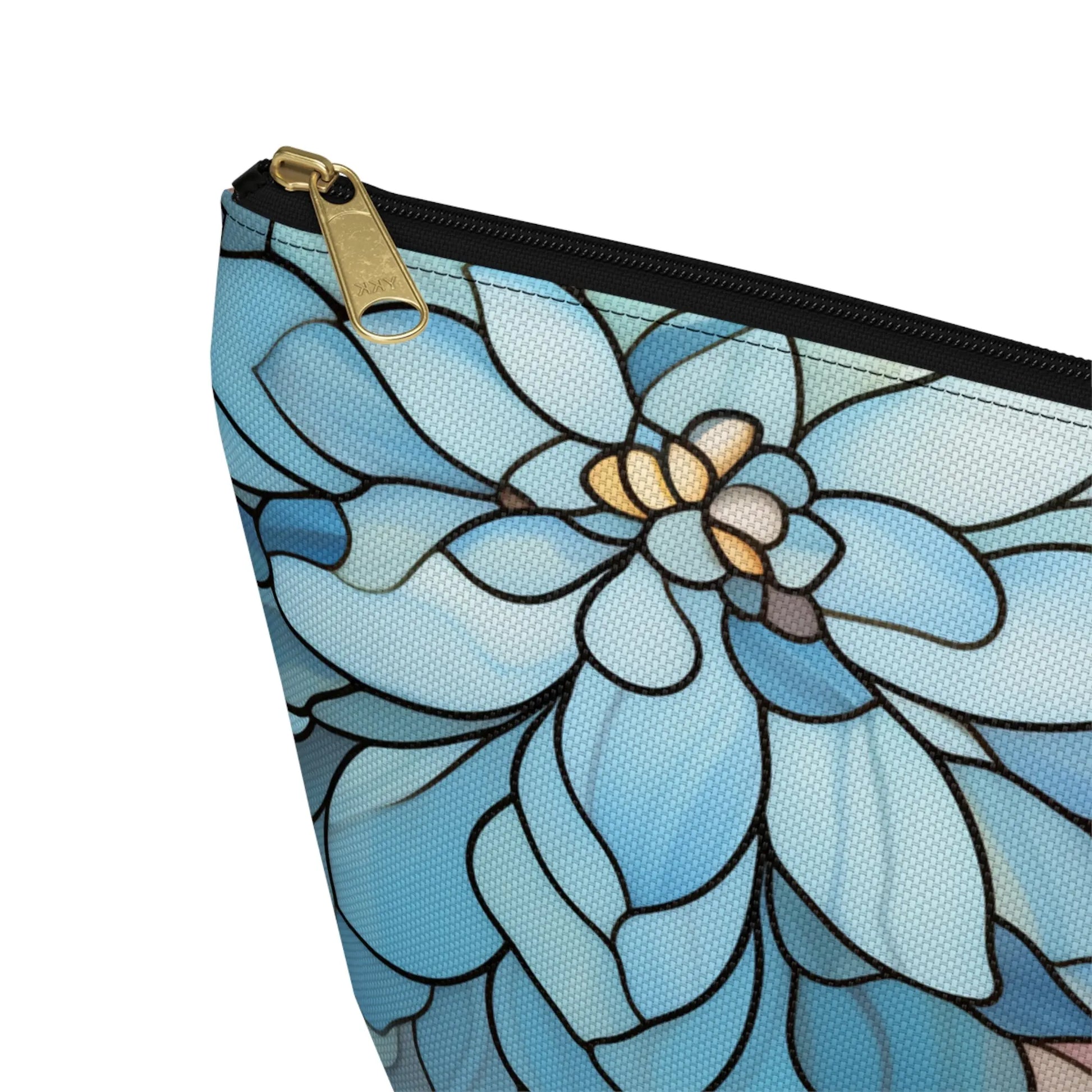 The Stained Glass Dark Flowers Cosmetic Bag, with its triangular shape and floral design, features large blue petals outlined in black and hints of white and yellow at the center. A black and gold zipper adds elegance, making it a perfect boho gift.