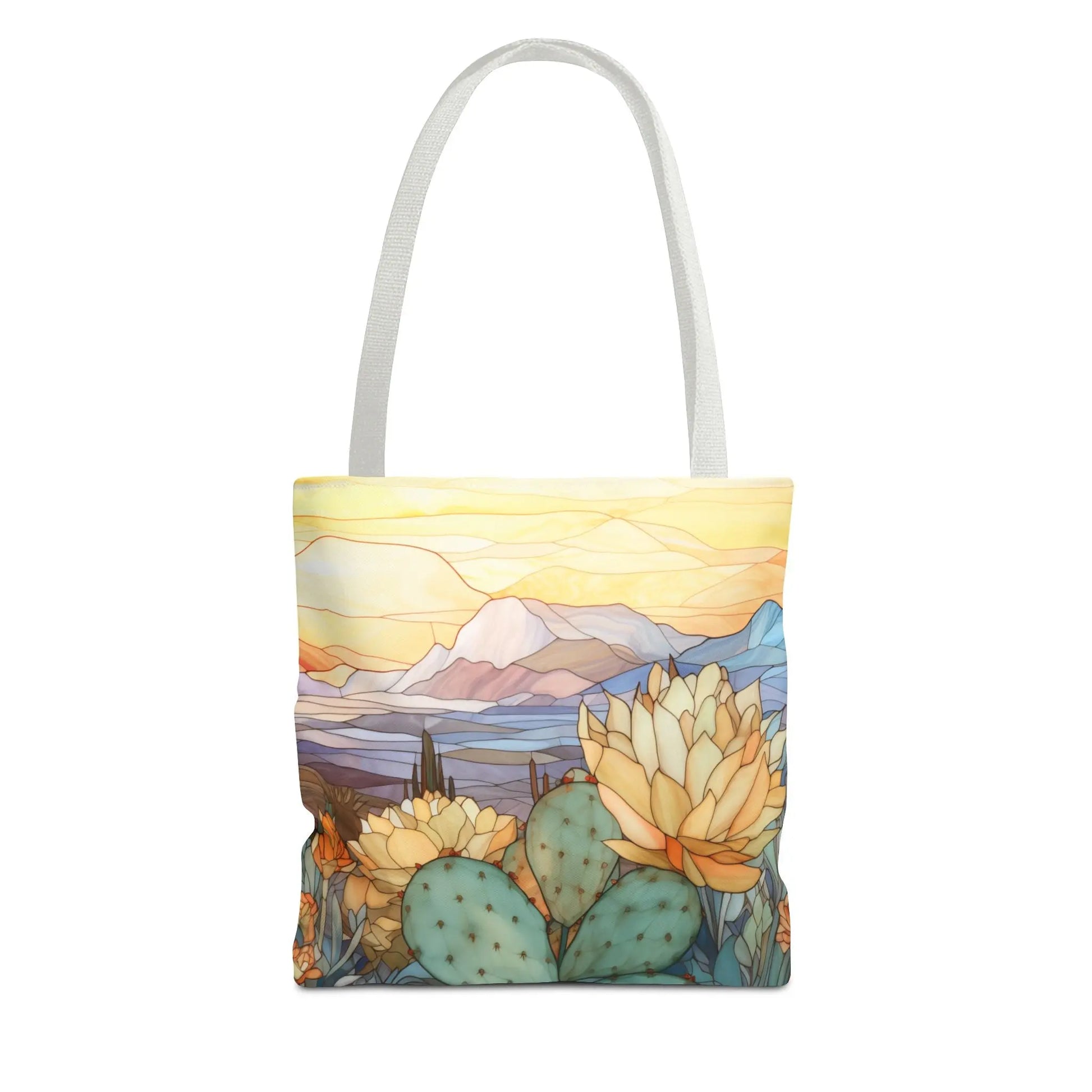 The Stained Glass Desert Cactus Tote Bag showcases a vibrant desert scene with blooming cacti and mountains beneath a colorful sky. Crafted from durable polyester, the artwork features pastel yellow, blue, and green hues, complemented by white handles. Available in 3 sizes.