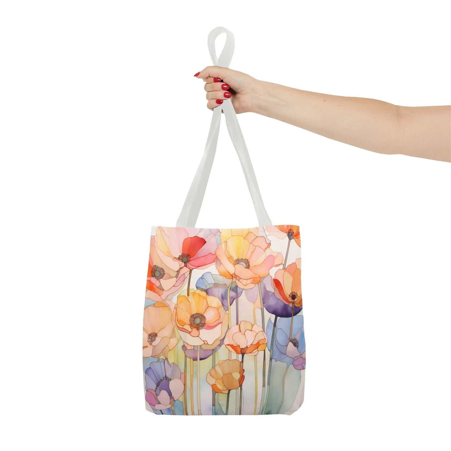 A person with red nail polish holds a durable polyester tote bag by its white handles. The Stained Glass Poppy Flowers Tote Bag features a vibrant floral design with orange, pink, and purple flowers, resembling a stained glass pattern against a white background.