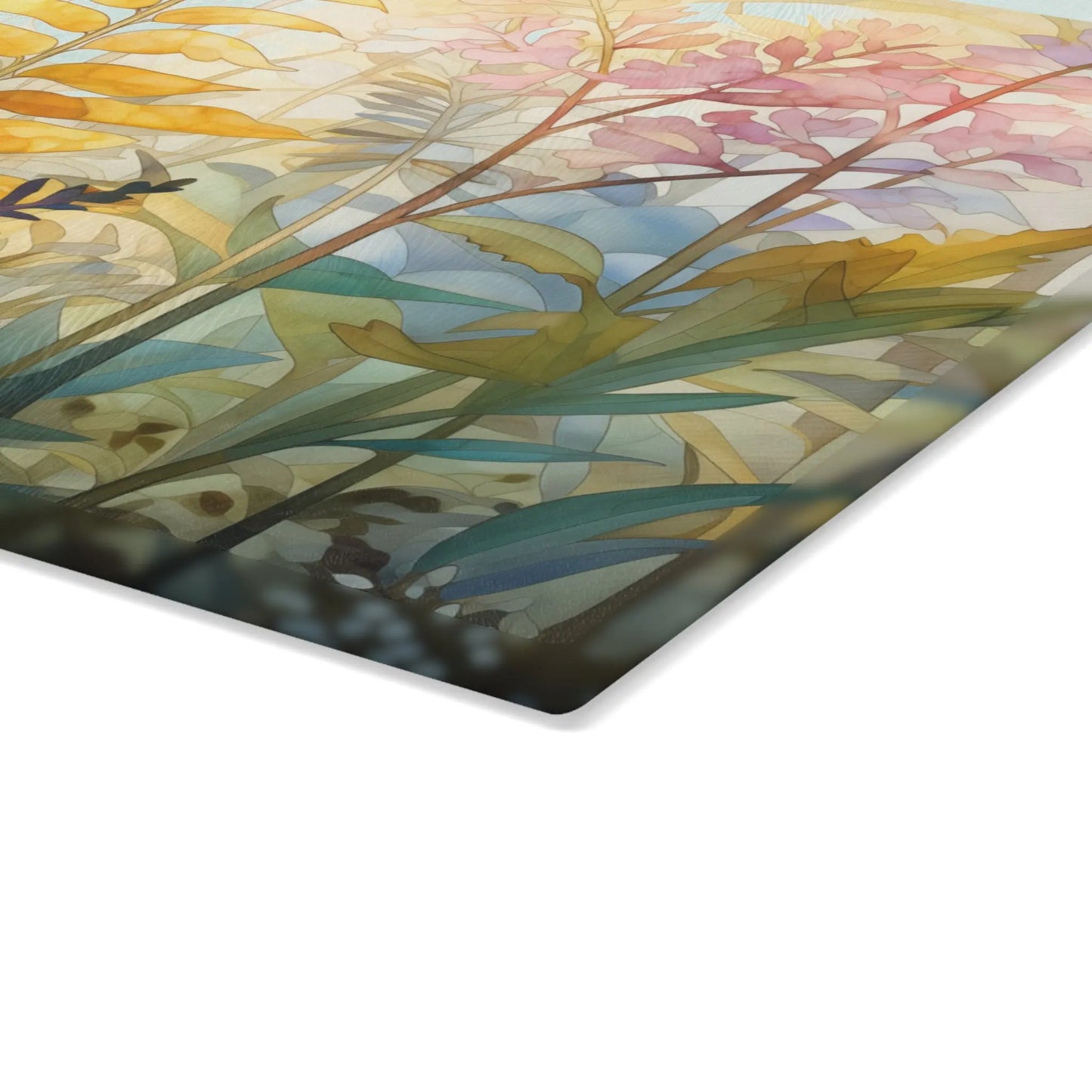 A close-up of the Stained Glass Pastel Ferns Glass Cutting Board reveals a colorful, abstract artwork. It features overlapping autumn leaves in shades of yellow, pink, and green with a soft watercolor texture, displayed on a slanted rectangular surface with a white background.