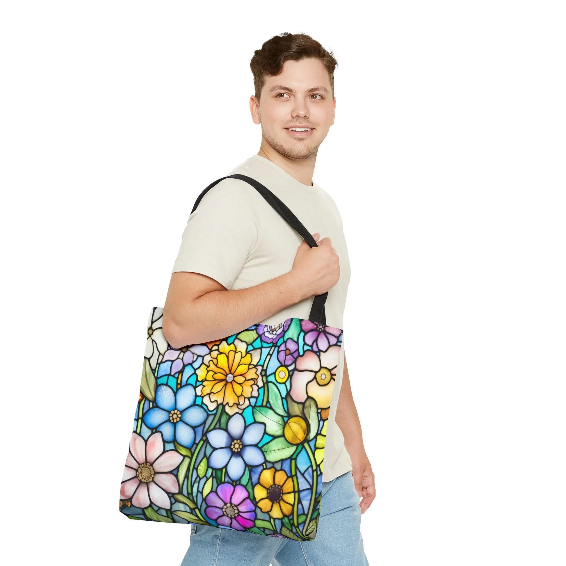 A person with short brown hair carries the Stained Glass Folk Art Flowers Tote Bag, featuring a vibrant and original artist design inspired by stained glass. They wear a light beige shirt and light blue jeans.