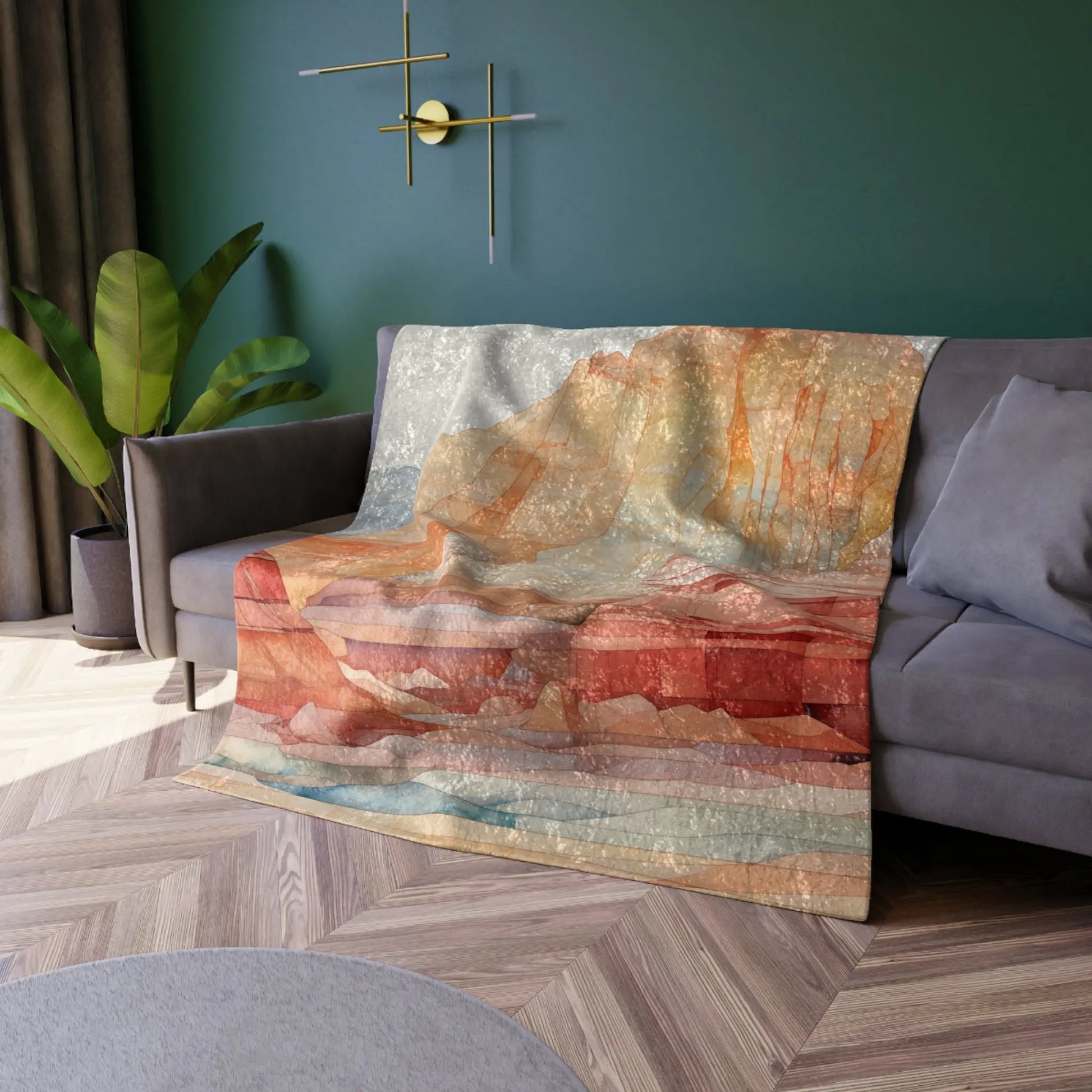 A vibrant Stained Glass Sedona Red Rocks Crushed Velvet & Fleece Blanket - 50x60 is draped over a gray sofa in a modern living room, featuring a green wall, brass wall lamp, potted plant, and herringbone wood floor.