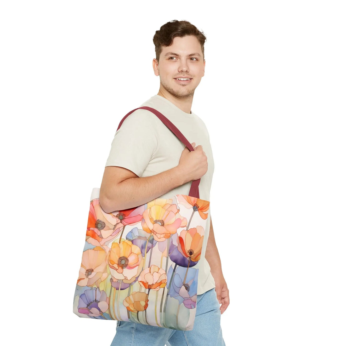 A person in a light gray T-shirt and blue jeans carries the Stained Glass Poppy Flowers Tote Bag, featuring a vibrant stained glass design with orange, yellow, and purple flowers. The tote has a dark red polyester strap. They are smiling while looking over their shoulder.