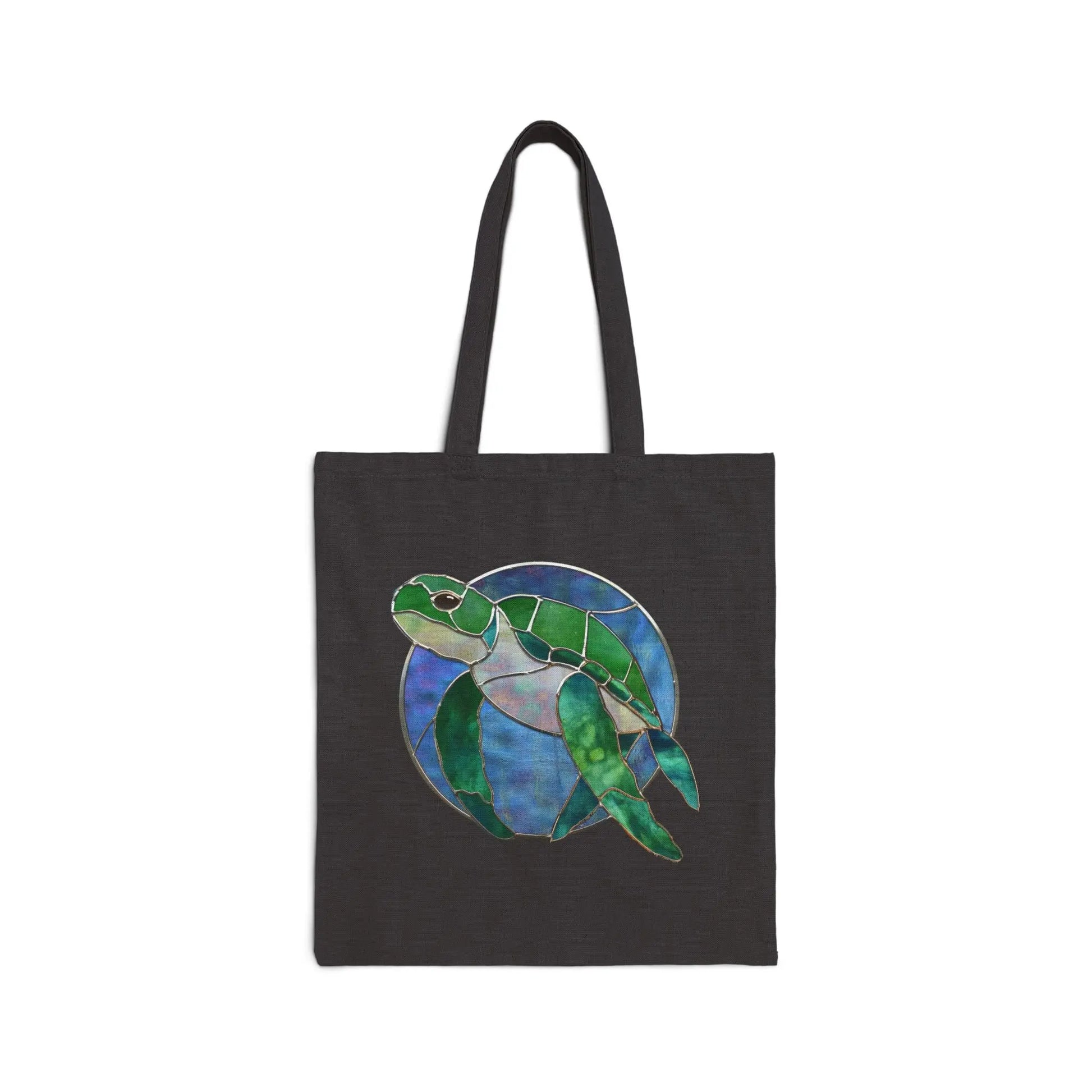The Stained Glass Turtle Cotton Canvas Tote Bag showcases a green sea turtle swimming elegantly against a circular blue and purple background.