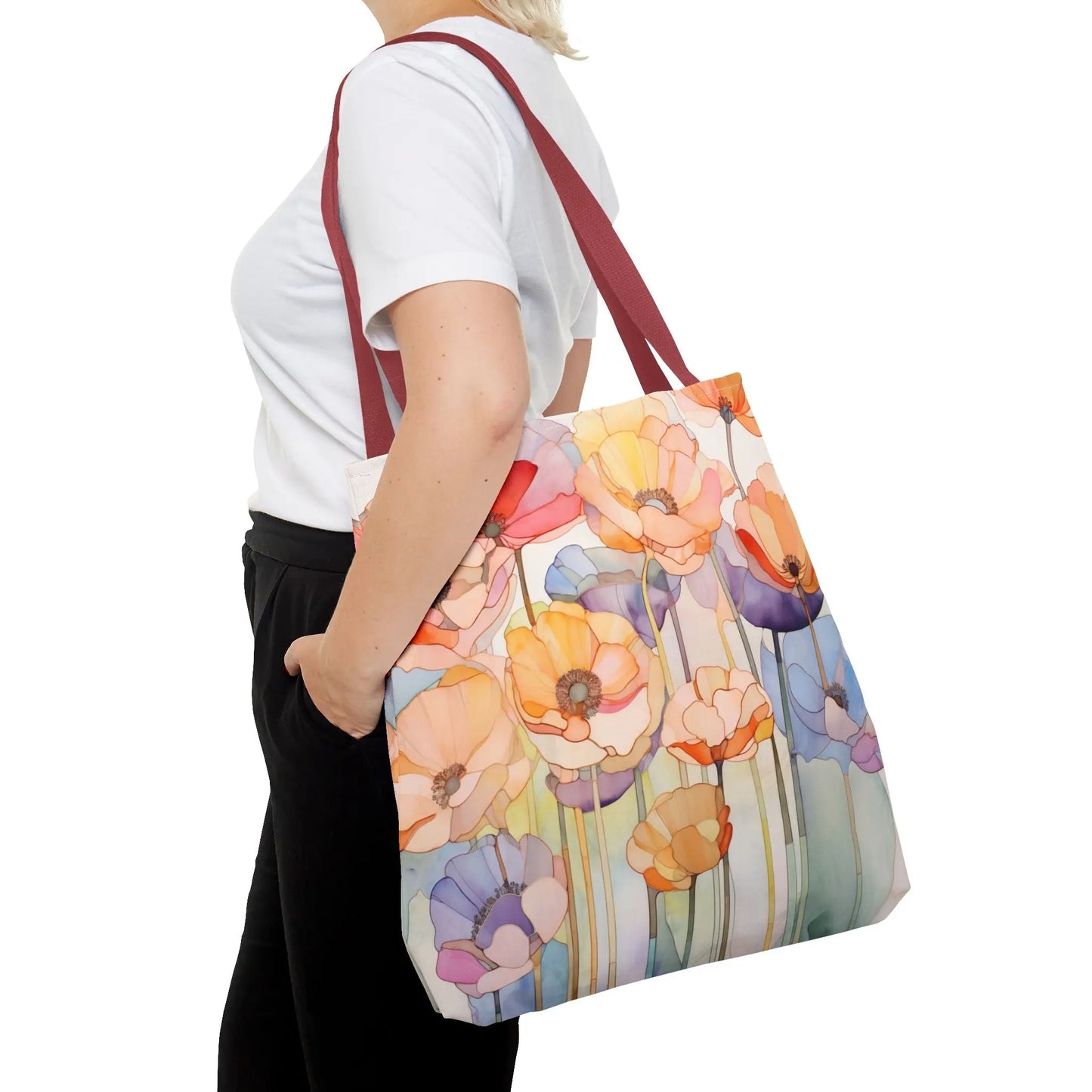 A person carries a Stained Glass Poppy Flowers Tote Bag, showcasing colorful floral designs on durable polyester. Dressed in a white shirt and black pants, they hold the bag by its bold red handles.