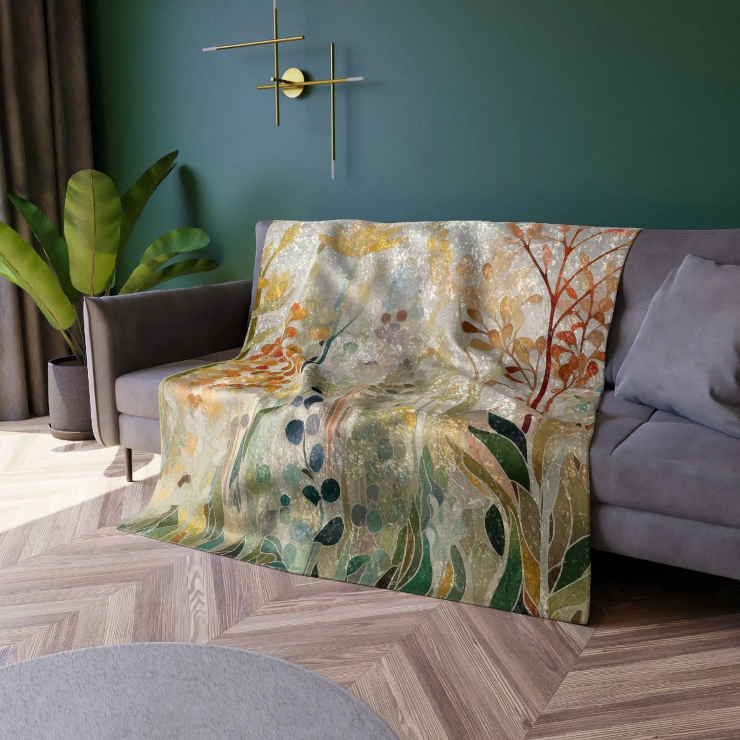 A Stained Glass Fall Flowers blanket with abstract leaf and branch patterns is draped over a gray couch. The room includes green walls, a round wall clock, a potted plant, and a geometric wooden floor.