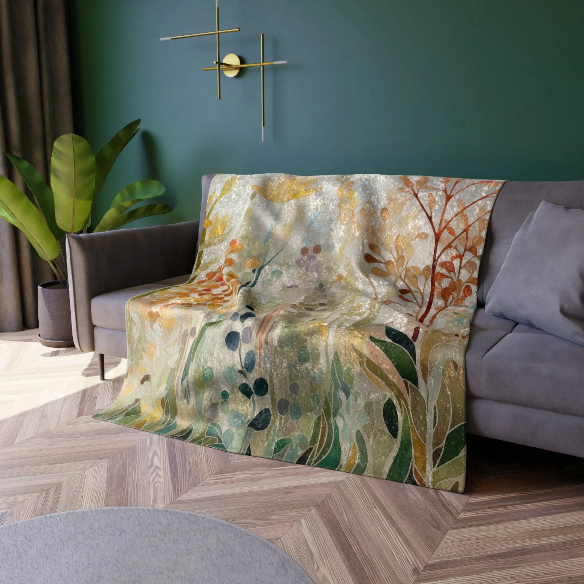 A Stained Glass Fall Flowers blanket with abstract leaf and branch patterns is draped over a gray couch. The room includes green walls, a round wall clock, a potted plant, and a geometric wooden floor.