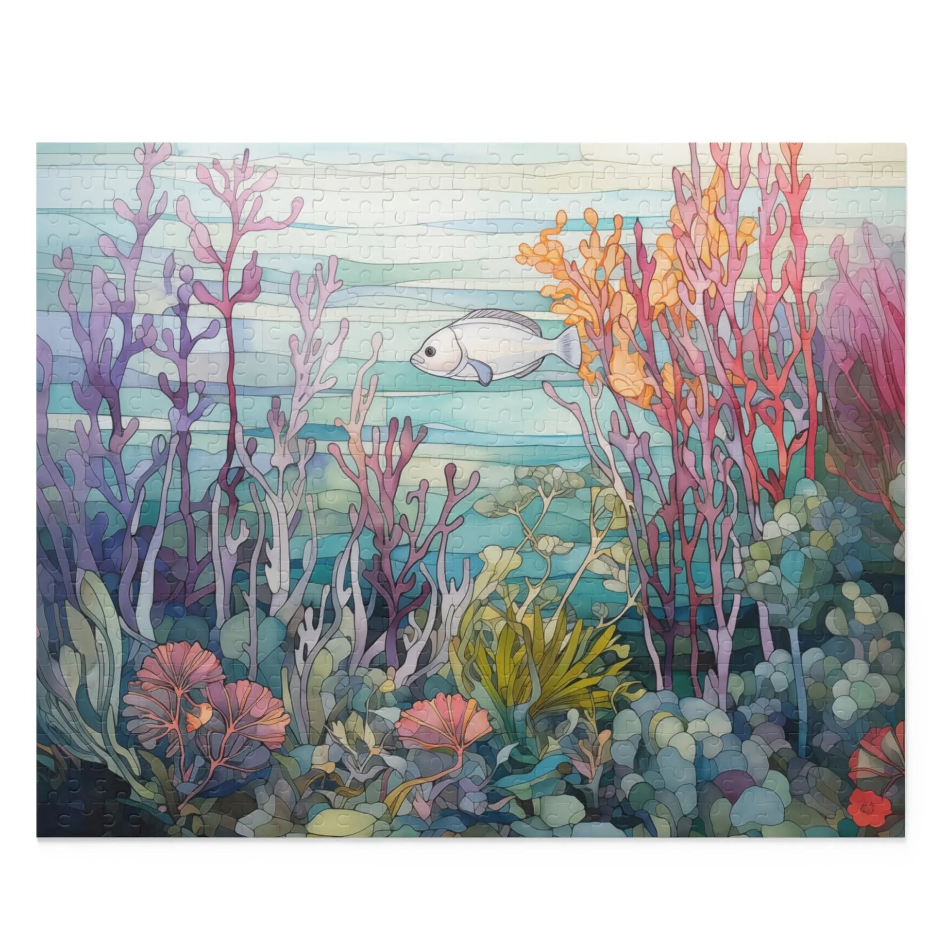 The Coral Reef Ocean Jigsaw Puzzle features an underwater scene with vibrant corals and plants in pink, purple, orange, and green hues. A lone fish swims near the center amid a soft blue-green gradient background, creating a sense of ocean depth.