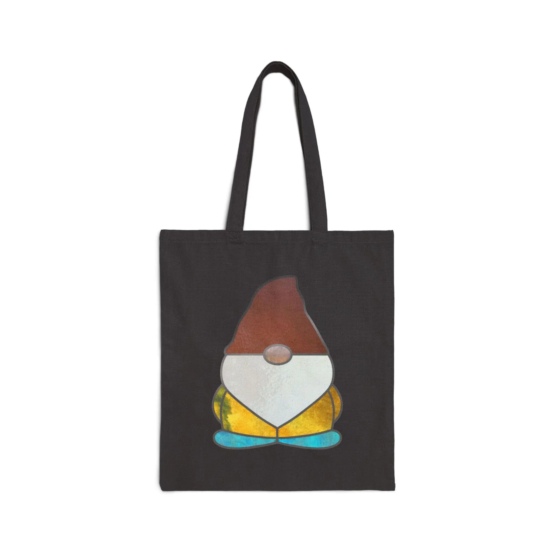 A black cotton canvas tote bag featuring a stained glass design gnome with a pointy hat and round nose in shades of brown, white, yellow, and blue.