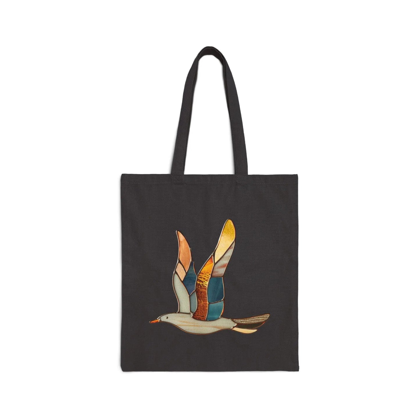 The Stained Glass Seagull Cotton Canvas Tote Bag is a black bag with a vibrant design showcasing a stylized seagull in flight, featuring wings with colorful patches of orange, yellow, and blue.