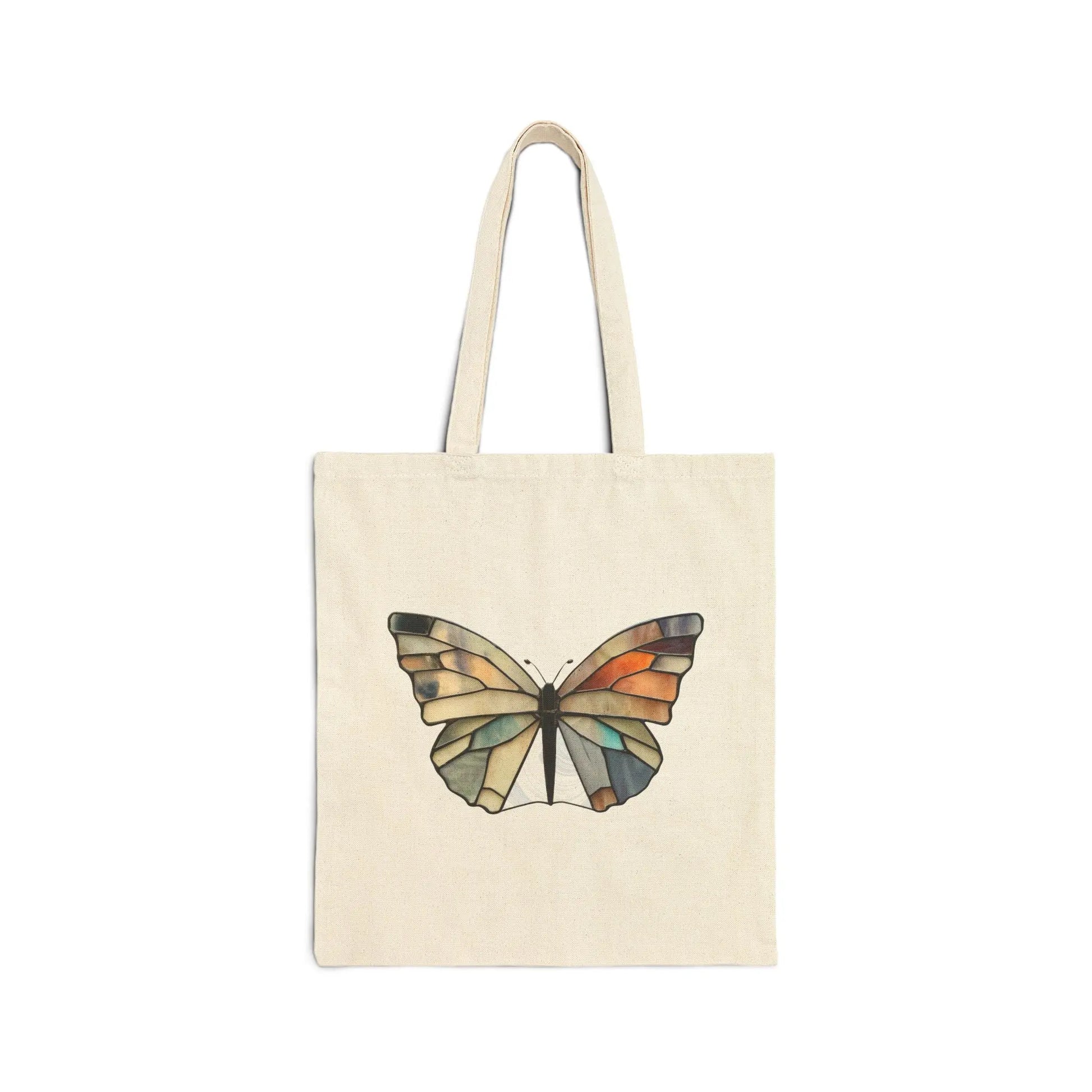 The Stained Glass Summer Butterfly Cotton Canvas Tote Bag, designed by Noelle Barnes, showcases a colorful butterfly with geometric orange, green, and blue patterns on a beige canvas. It features two sturdy handles and is attractively presented against a white backdrop.