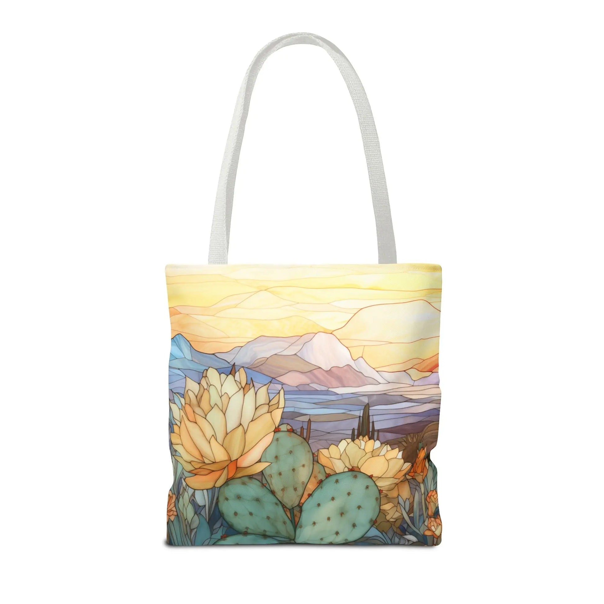 The Stained Glass Desert Cactus Tote Bag features durable polyester with an artist-designed, stained glass-style desert landscape of blooming yellow flowers, green cactus, and mountains beneath a vibrant sunset. It includes sturdy white straps for easy carrying.