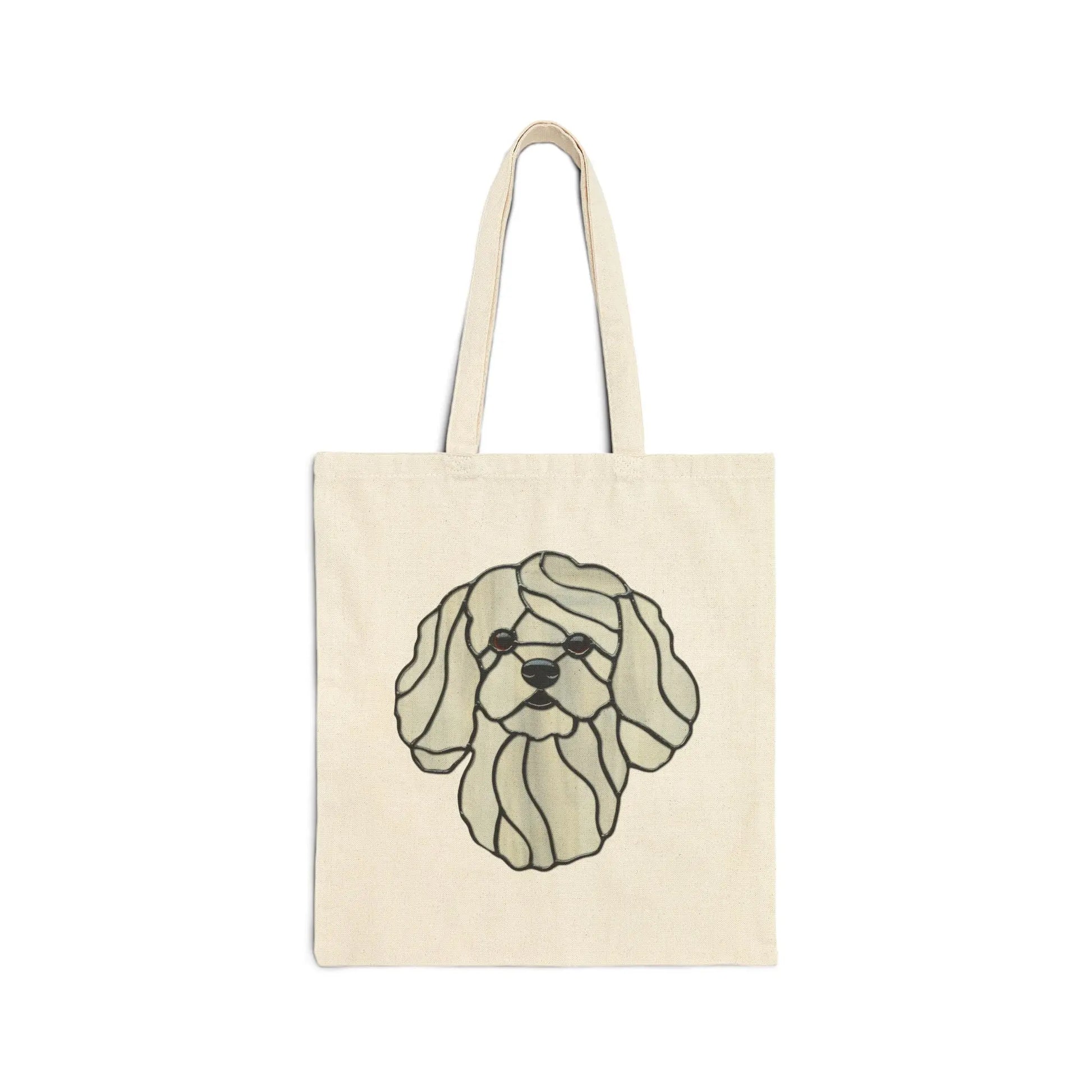 The Stained Glass Bichon Frise Cotton Canvas Tote Bag is beige and features a stylized illustration of a dogs face with floppy ears, outlined in black. The simple, flowing design evokes stained glass and is crafted using eco-friendly methods.