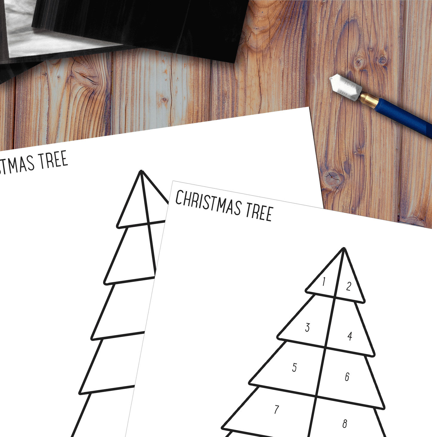 A top-down view of a wooden desk shows two Beginner Christmas Tree Rainbow Stained Glass Pattern templates with numbered sections for a project. A pencil with an eraser lies beside the papers, ready to help you create your suncatcher masterpiece.