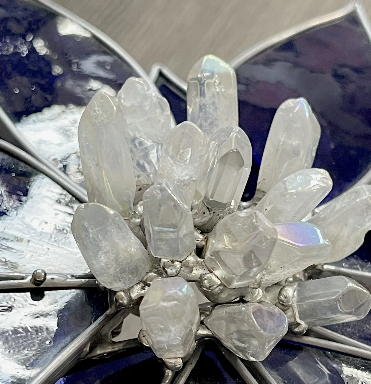 A close-up of the Handmade Stained Glass Flower and Crystal Suncatcher - XL Blue displays a cluster of translucent crystals, accented by dark blue and metallic petals, offering contrast and elegance.