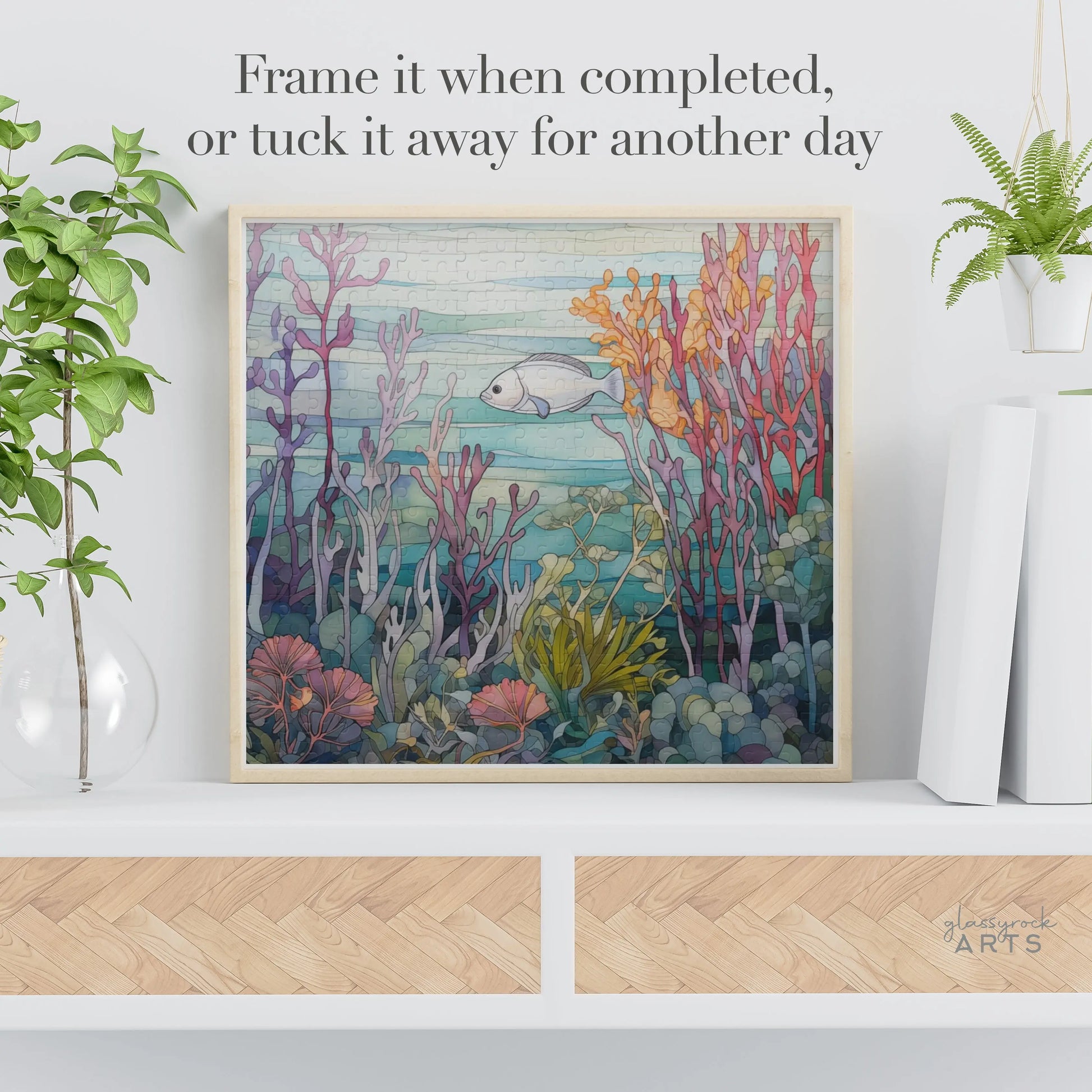 The Coral Reef Ocean Jigsaw Puzzle features a vibrant underwater scene with fish, coral, and sea plants. Perfect for display on a shelf with plants, its an ideal art gift. Text suggests: Frame it when completed or tuck it away for another day.