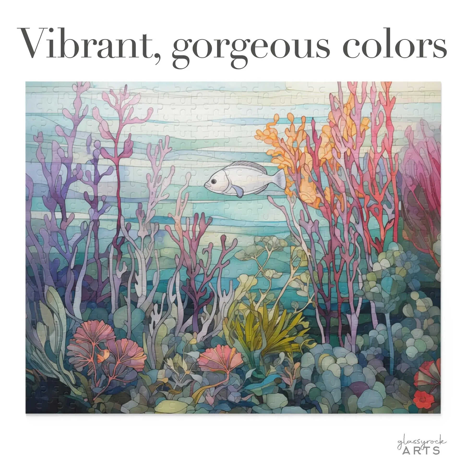 The Coral Reef Ocean Jigsaw Puzzle features a stained-glass-style illustration with vibrant coral in pink, purple, orange, and green hues. A white fish swims gracefully at the center beneath Vibrant, gorgeous colors.