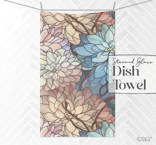 An ideal housewarming gift, the Stained Glass Dark Flowers Dish Towel features a stained glass design with large overlapping petals in blue, pink, and beige against white herringbone tiles.
