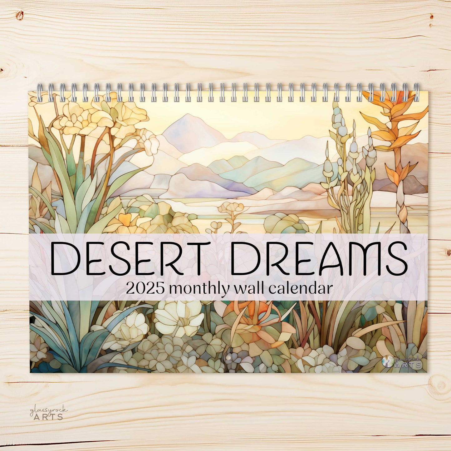 The 2025 Wall Calendar - Stained Glass Desert Landscapes, with spiral binding and a centered hole for hanging, features vivid desert illustrations.