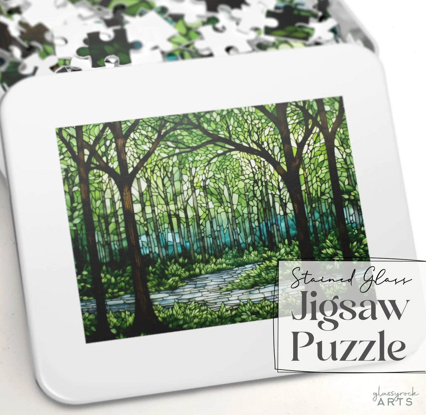 The Stained Glass Forest Jigsaw Puzzle box features a forest scene with tall trees and a river in stained glass style, surrounded by scattered pieces. It makes an exquisite gift for any nature lover.