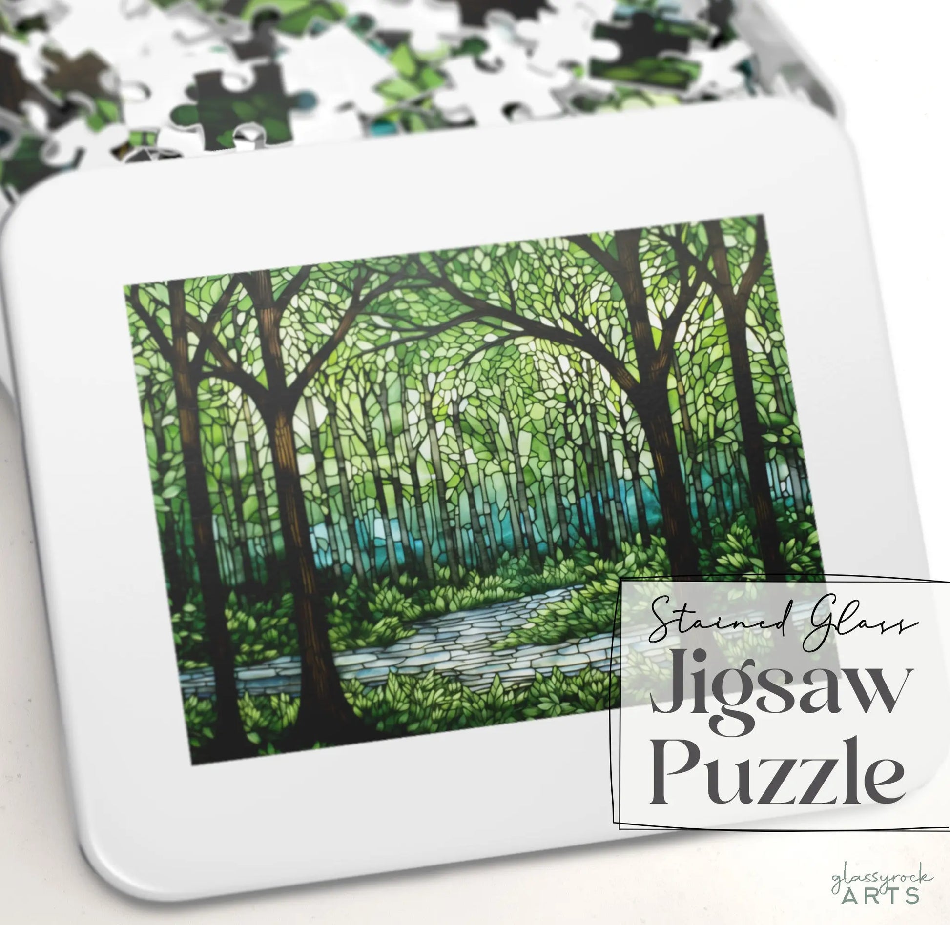 The Stained Glass Forest Jigsaw Puzzle box features a forest scene with tall trees and a river in stained glass style, surrounded by scattered pieces. It makes an exquisite gift for any nature lover.