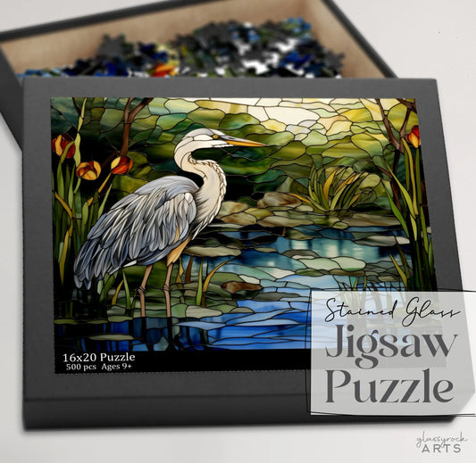 A jigsaw puzzle box featuring a colorful blue heron rendered in stained glass.