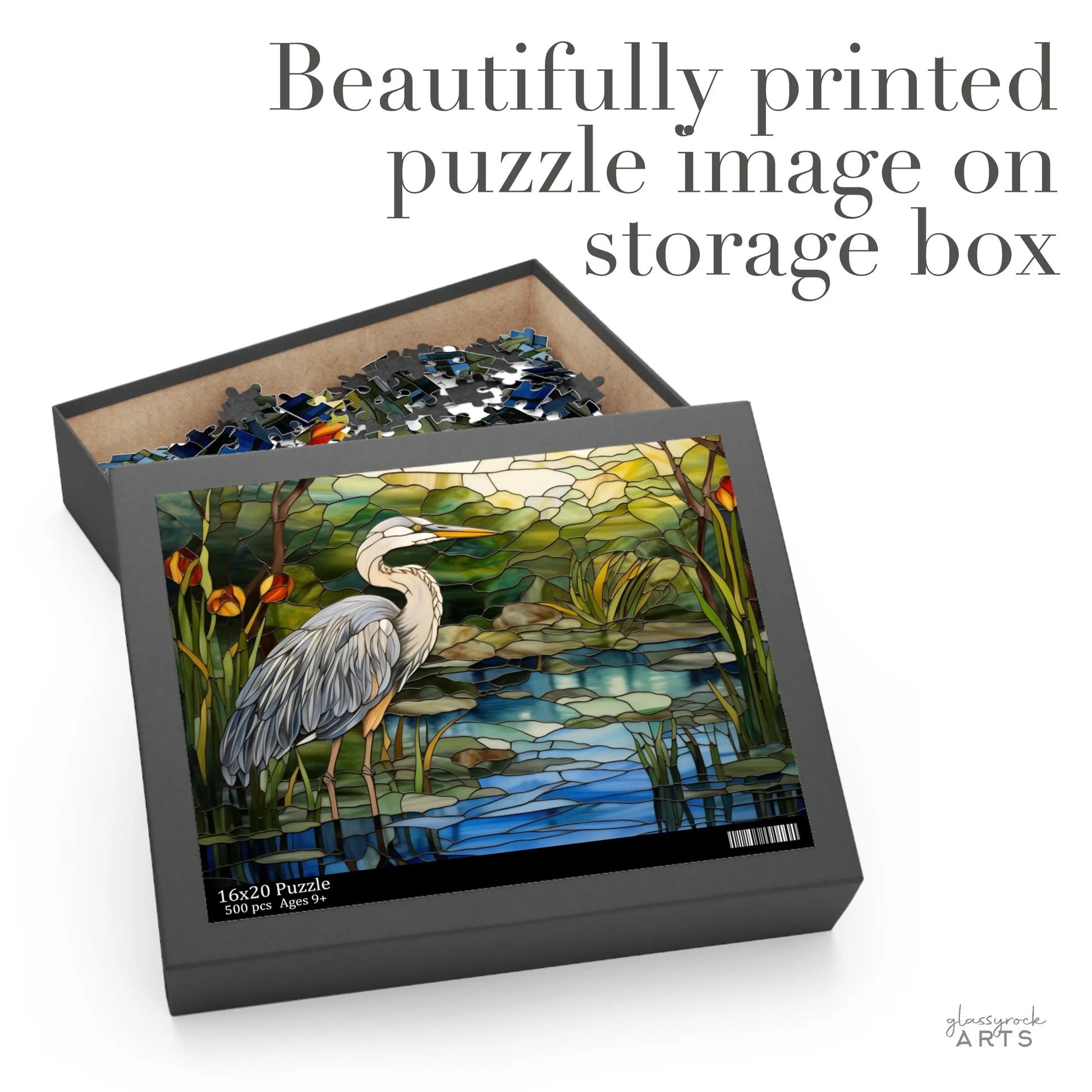 A jigsaw puzzle box featuring a colorful blue heron rendered in stained glass. It has a beautifully printed puzzle image on the top of the storage box.