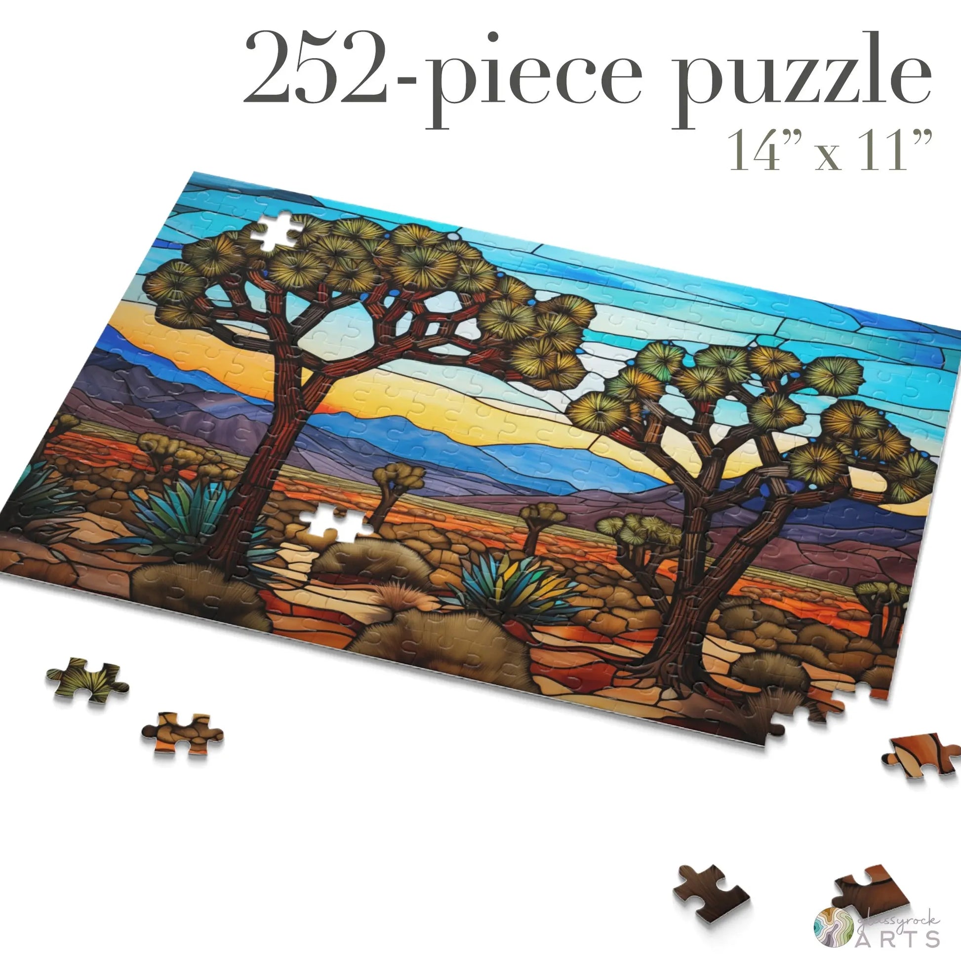The Joshua Tree National Park Jigsaw Puzzle, a vibrant 252-piece art gift, features a stunning desert landscape with two prominent trees, mountains, and a stained glass-like sky. It measures 14 x 11 and includes playfully scattered pieces.