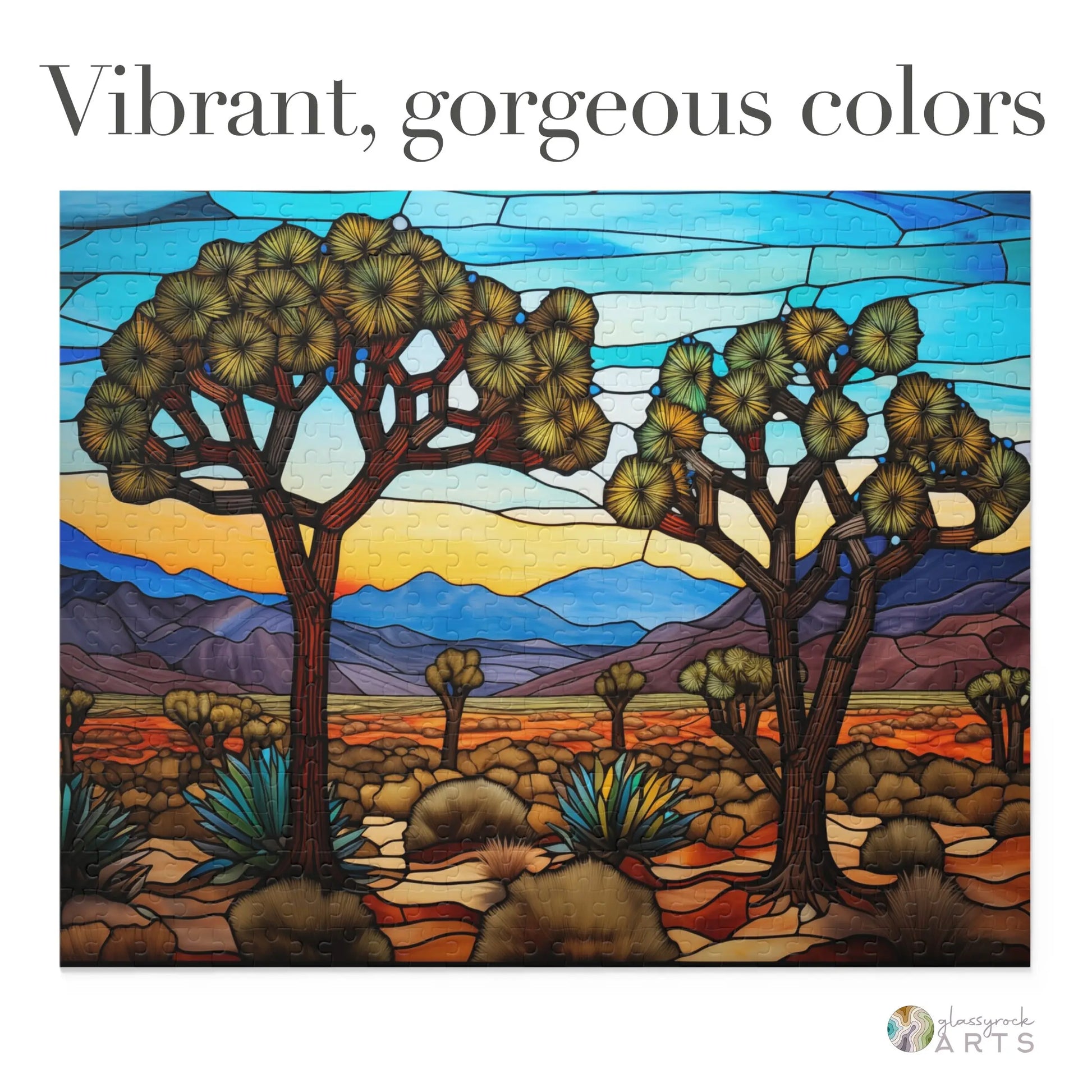 The Joshua Tree National Park Jigsaw Puzzle showcases a stained glass-style desert landscape inspired by the park, with two trees, colorful shrubs, and distant mountains. This art gift dazzles with its vibrant colors and features text: Vibrant, gorgeous colors.