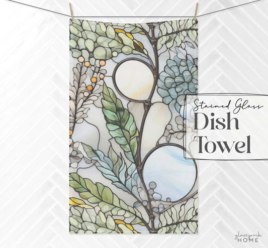 Against a white backdrop, this kitchen towel features intricate floral and leaf patterns in pastel greens, blues, and grays. The text Stained Glass Nouveau Ferns Dish Towel captures its essence as a custom creation inspired by stained glass masterpieces.