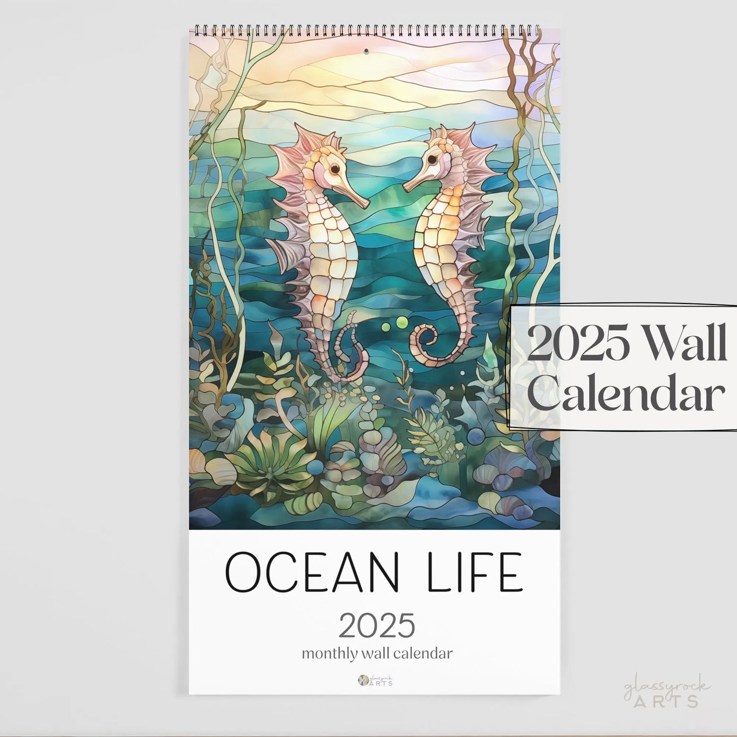 The 2025 Ocean Life Large Wall Calendar features vibrant seahorses amidst lush underwater plants, capturing the elegance and mystery of marine life in a stunning creation by Glaznost Arts.