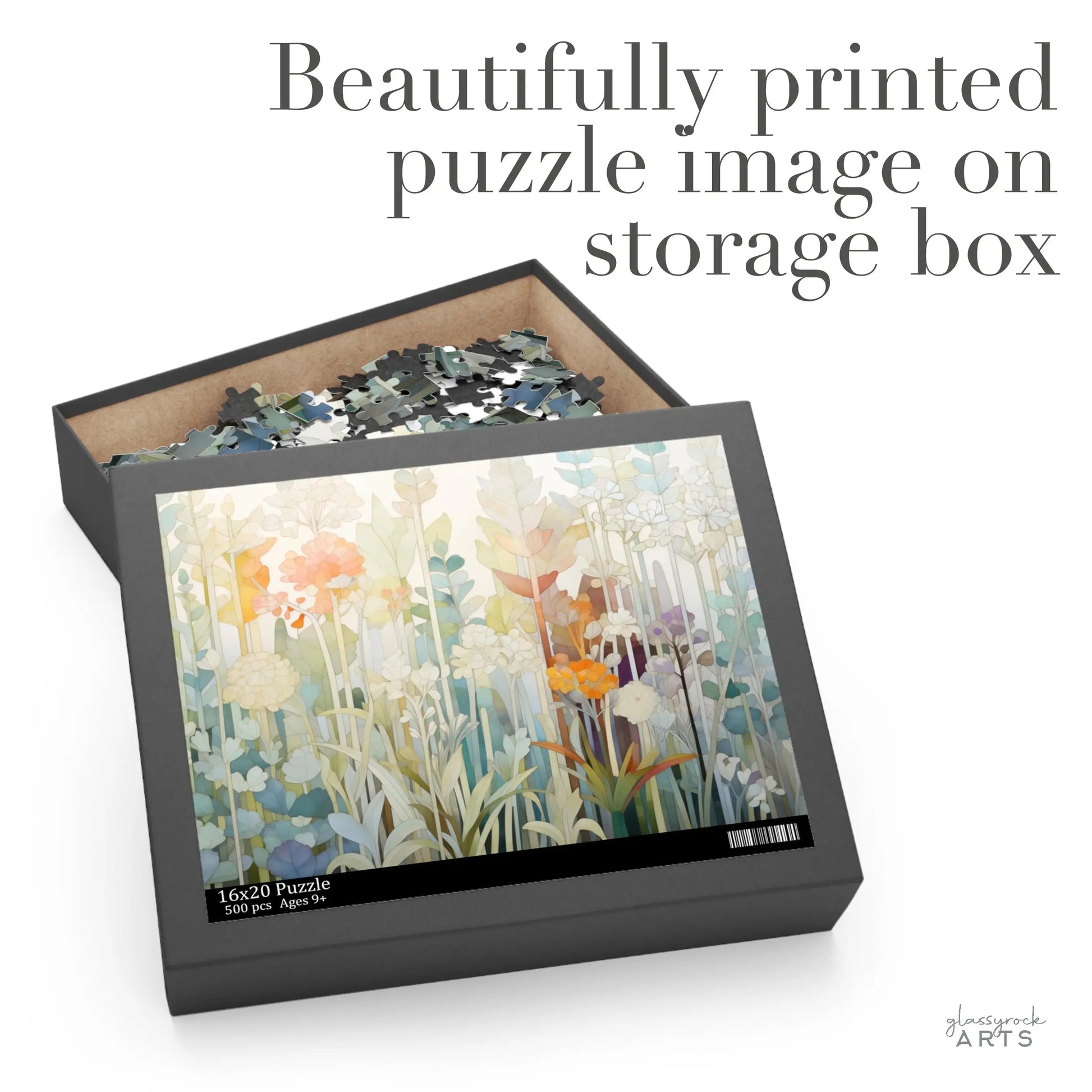 The open puzzle box reveals high-quality chipboard pieces inside. Its lid displays a colorful floral illustration with various flowers and leaves. Text above reads Beautifully printed puzzle image on storage box, ideal for any Pastel Botanicals Jigsaw Puzzle enthusiast.
