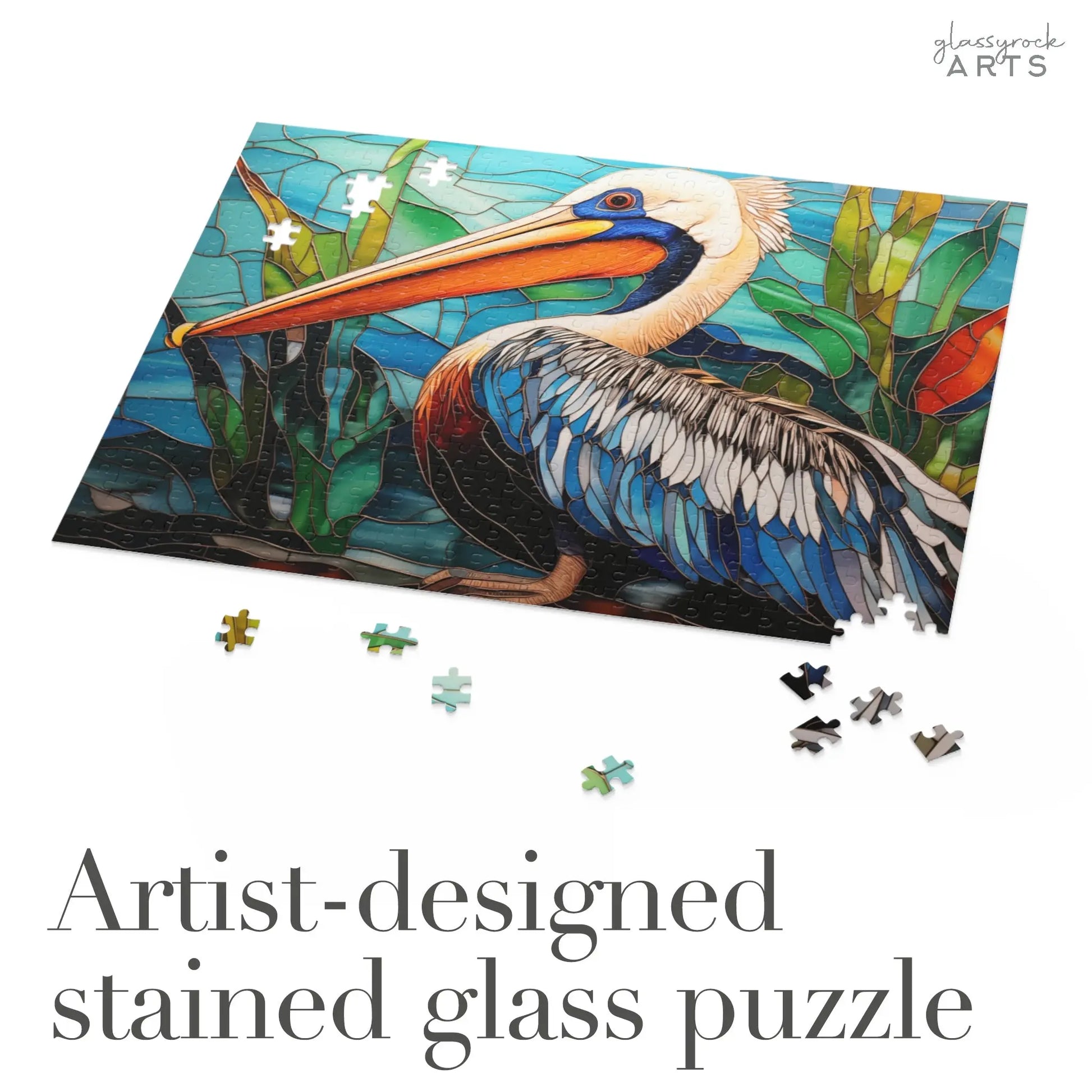 The Stained Glass Pelican Jigsaw Puzzle showcases a pelican with water and foliage, making it a perfect art gift or unique couples gift. Scattered pieces complete the design, while Artist-designed stained glass puzzle is inscribed below.