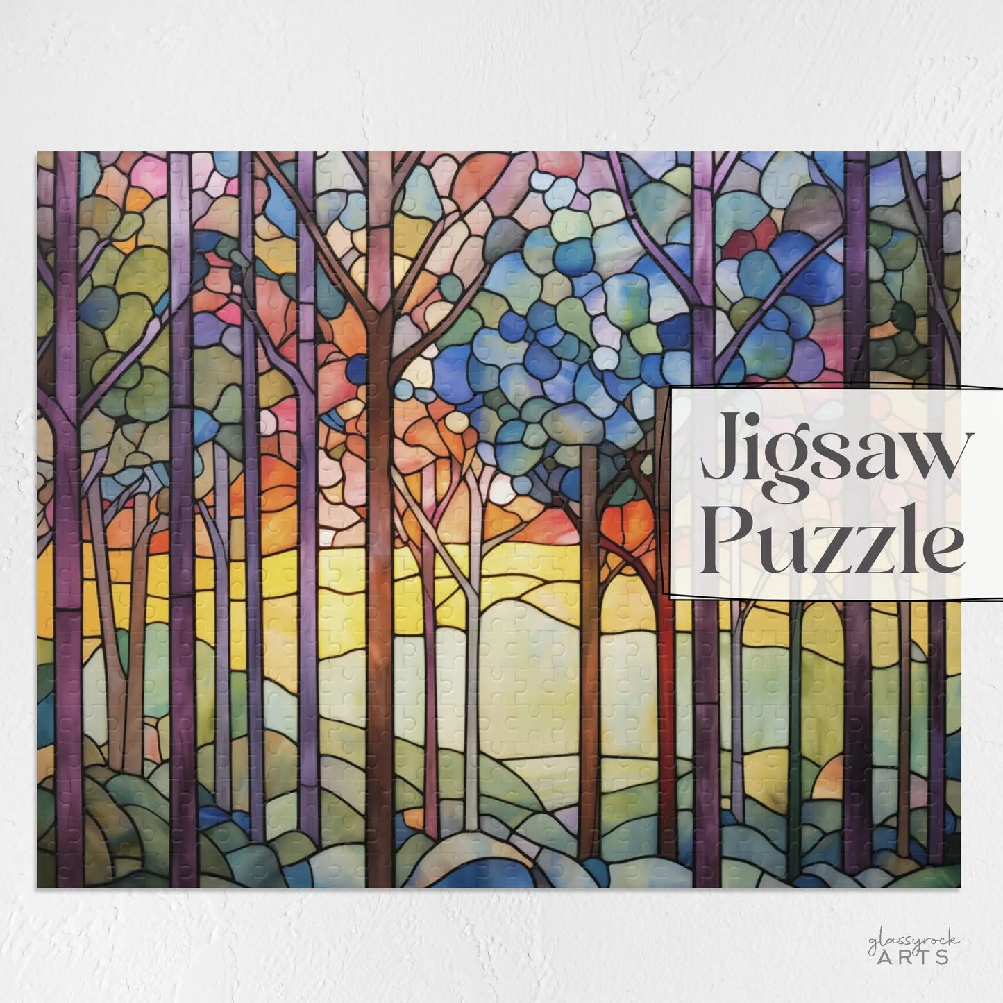 The Rainbow Forest Jigsaw Puzzle features a stained-glass-inspired scene with tall trees reaching skywards against vibrant sunrise or sunset hues, blending warm and cool tones. The text Jigsaw Puzzle is prominently displayed, making it an ideal nature-themed gift.