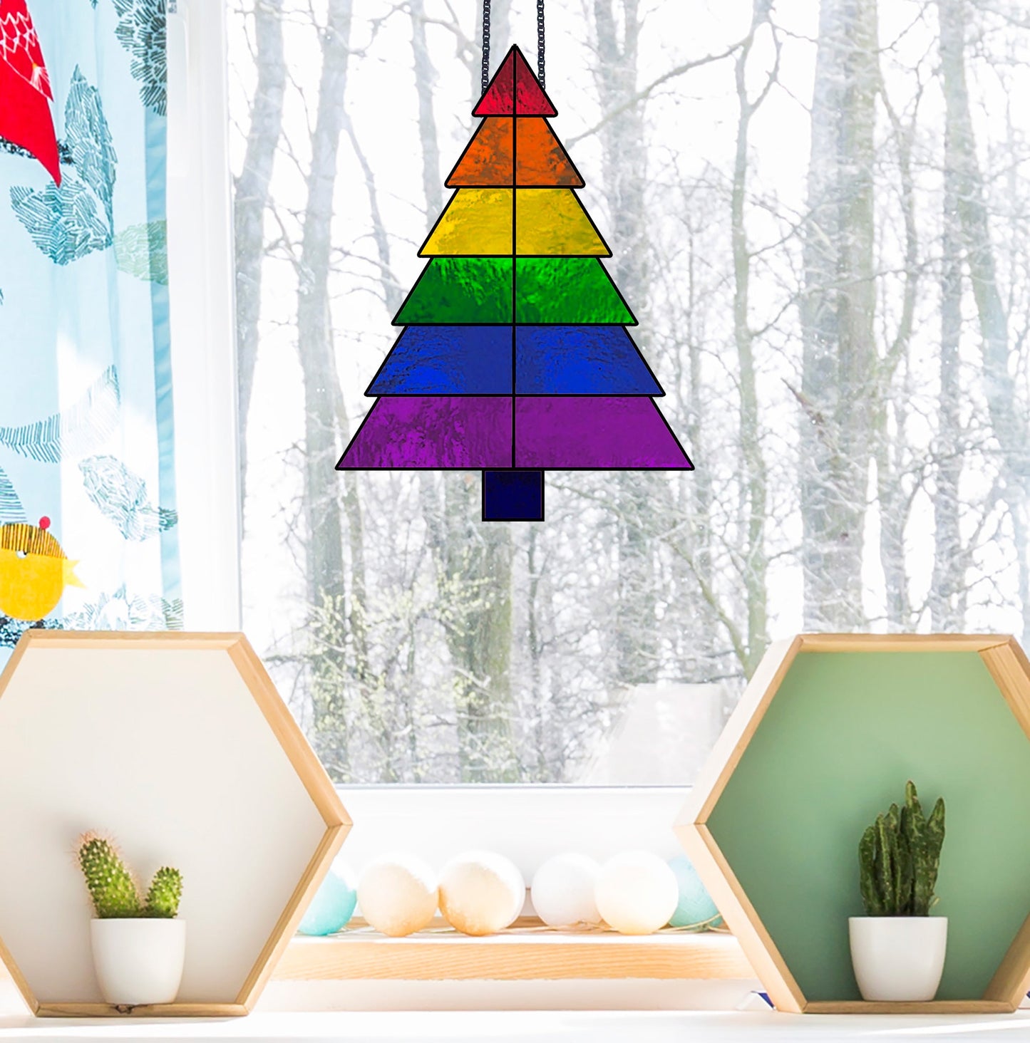 A Beginner Christmas Tree Rainbow Stained Glass Pattern hangs in the window, with snow-covered trees outside and hexagonal shelves of small cacti on each side, creating a serene contrast of nature and art for beginners to admire and recreate.