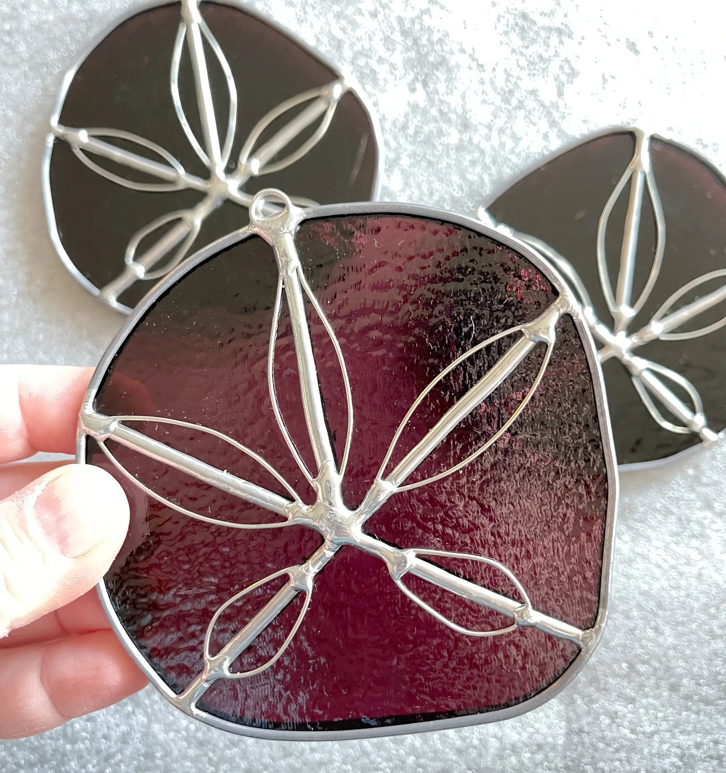 Three purple handmade stained glass sand dollars with handworked wire accents