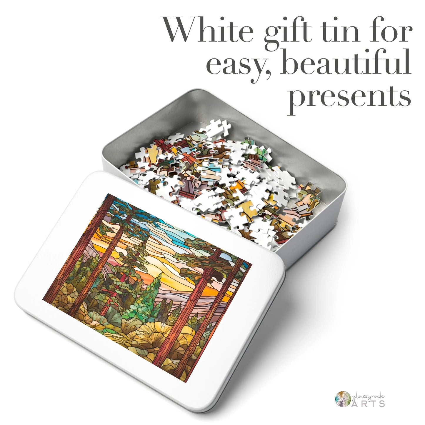 White gift tin with puzzle pieces inside, showcasing a Stained Glass Sequoia Forest Jigsaw Puzzle image on the lid. The text reads: White gift tin for easy, beautiful presents―the perfect gift for puzzle lovers.