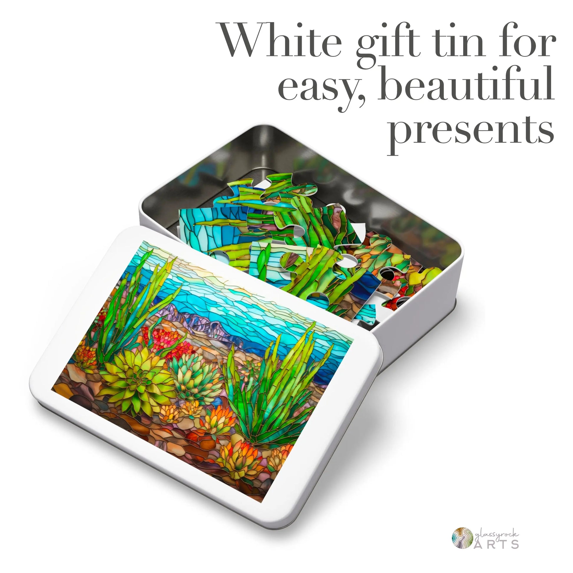 White gift tin with a mosaic-style design of cacti and desert scenery, similar to the Stained Glass Succulents Jigsaw Puzzle. Slightly open lid shows more vibrant patterns inside, labeled White gift tin for easy, beautiful presents.