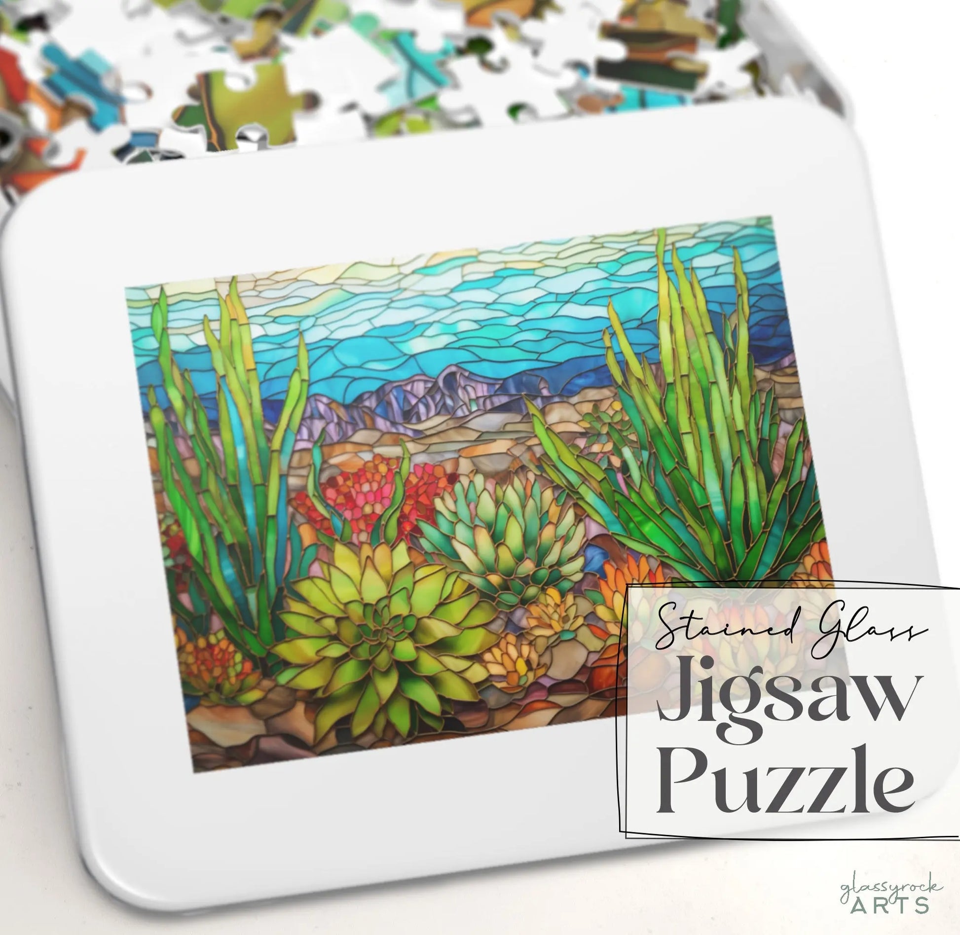 A gift-ready puzzle tin with vibrant stained glass artwork of desert succulents and mountains is labeled Stained Glass Succulents Jigsaw Puzzle. Perfect for enthusiasts, it offers hours of artistic enjoyment.