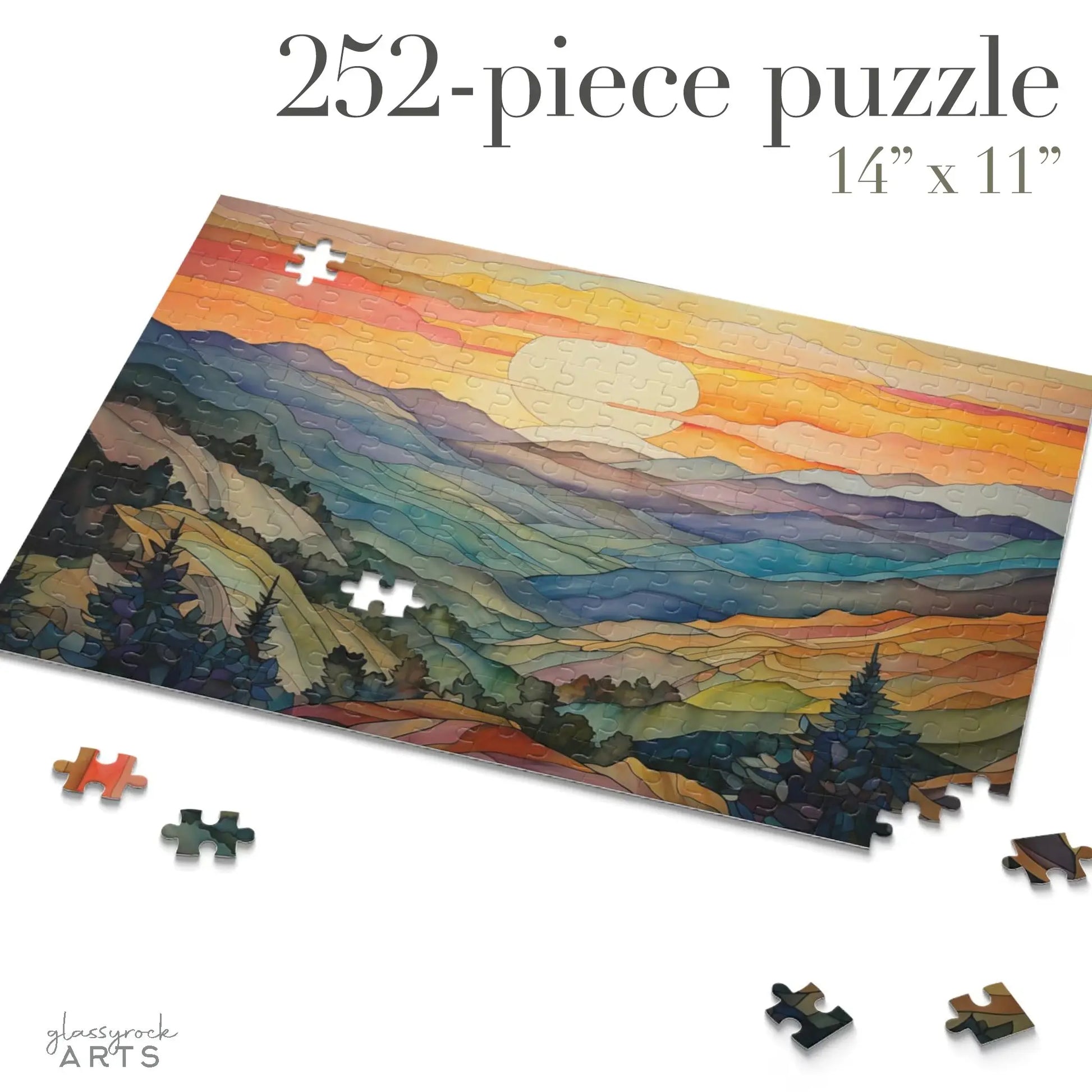 A partially completed Sunset Mountains Jigsaw Puzzle, with 252 pieces and measuring 14 x 11, showcases a colorful landscape of mountains and a setting sun. Ideal for nature lovers, the artwork blends warm and cool hues, with some pieces scattered around the puzzle.