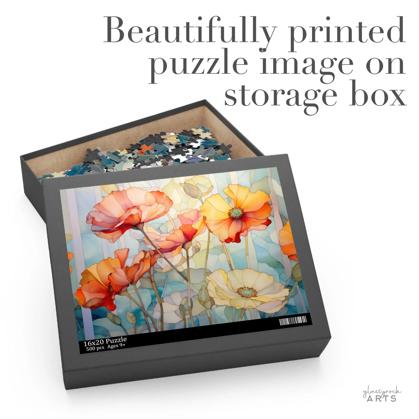 The Watercolor Poppies Jigsaw Puzzle box opens to reveal vibrant flower pieces. The lid displays a stunning art print of orange and white poppies with green stems on a blue background, ideal for puzzle enthusiasts. Text reads, Beautifully printed puzzle image on storage box.